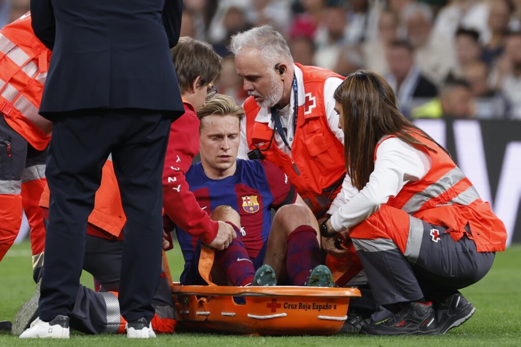 epa11292808 Dutch midfielder of FC Barcelona Frenkie de Jong leaves the field on a stretcher during the LaLiga soccer match between Real Madrid and FC Barcelona, at the Santiago Bernabeu stadium in Madrid, Spain, 21 April 2024.  EPA-EFE/Daniel Gonzalez