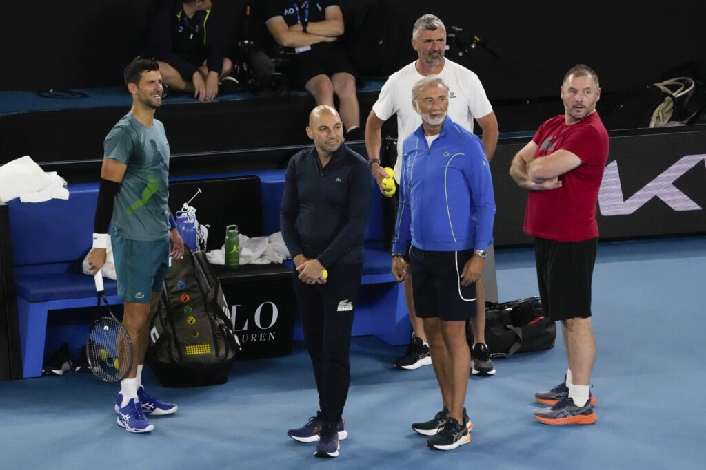 Serbia's Novak Djokovic, left, stands with his team during a practice session ahead of the Australian Open tennis championships at Melbourne Park, Melbourne, Australia, Saturday, Jan. 13, 2024. (AP Photo/Andy Wong)