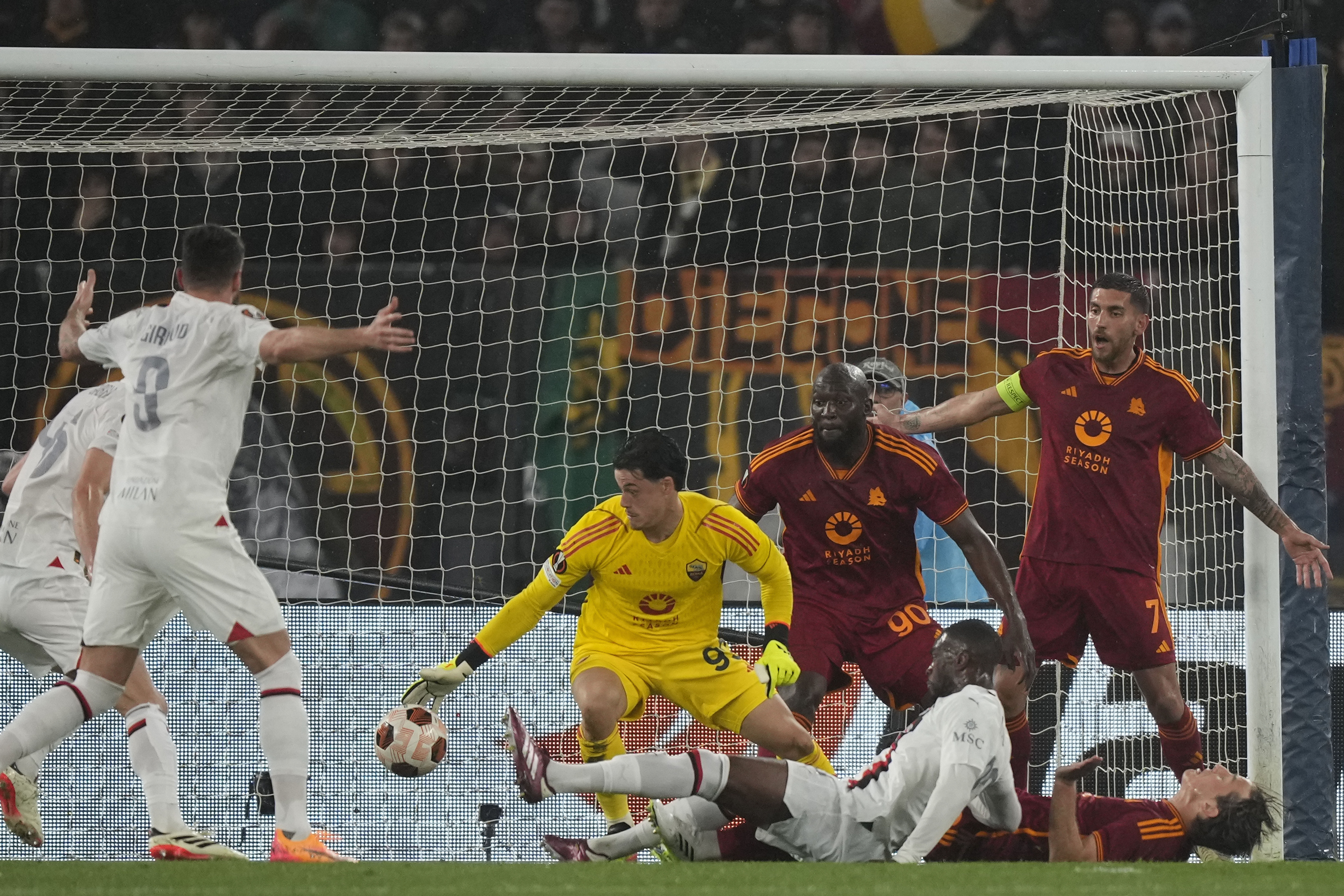 Roma's goalkeeper Mile Svilar, center, stops the ball from entering the net during the Europa League quarterfinal second leg soccer match between Roma and AC Milan, at Rome's Olympic Stadium, Thursday, April 18, 2024. (AP Photo/Andrew Medichini)