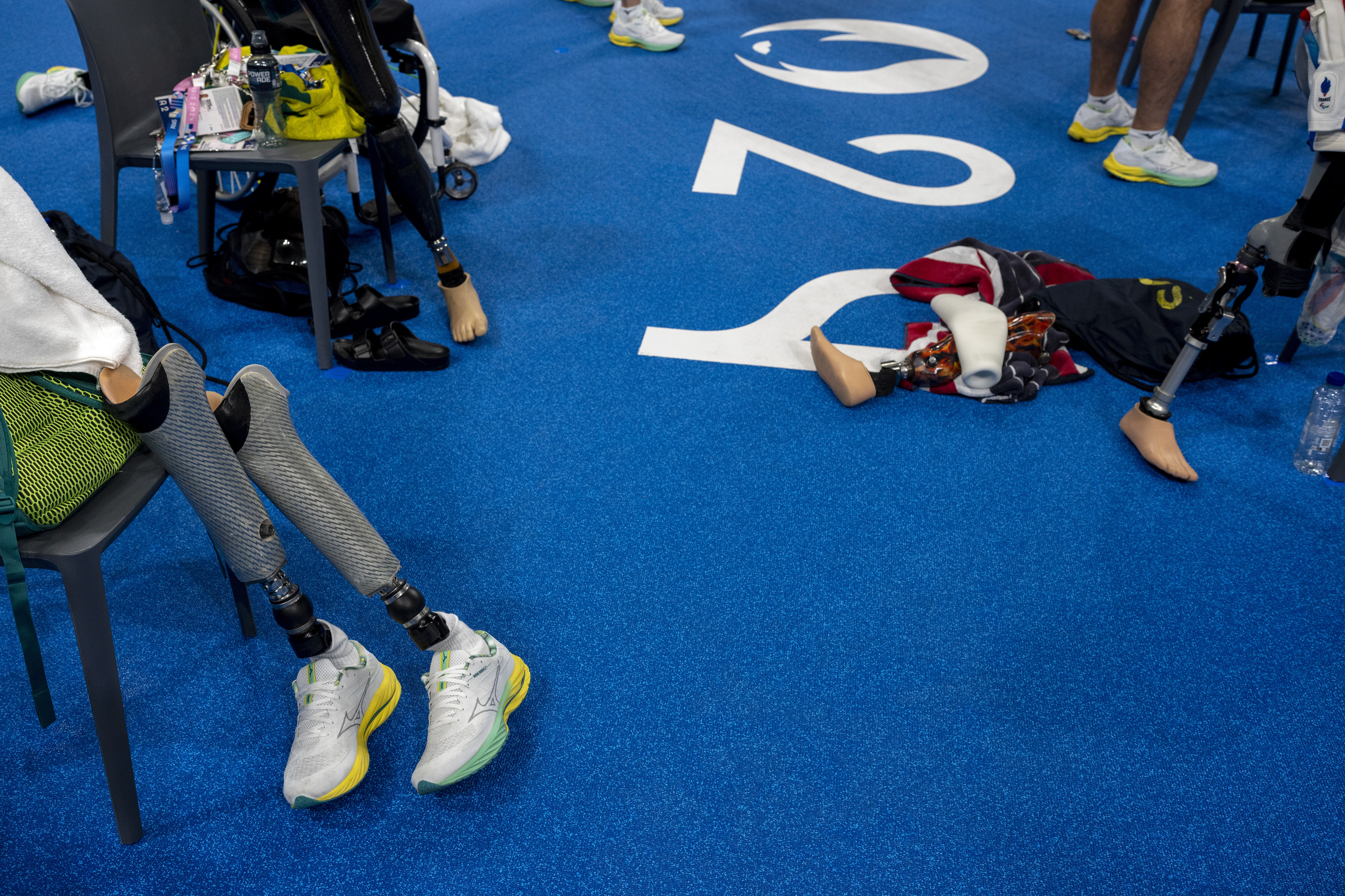Prosthetic legs of Paralympic athletes lying poolside during a training session ahead of the 2024 Paralympics, Wednesday, Aug. 28, 2024, in Paris, France. (AP Photo/Emilio Morenatti)