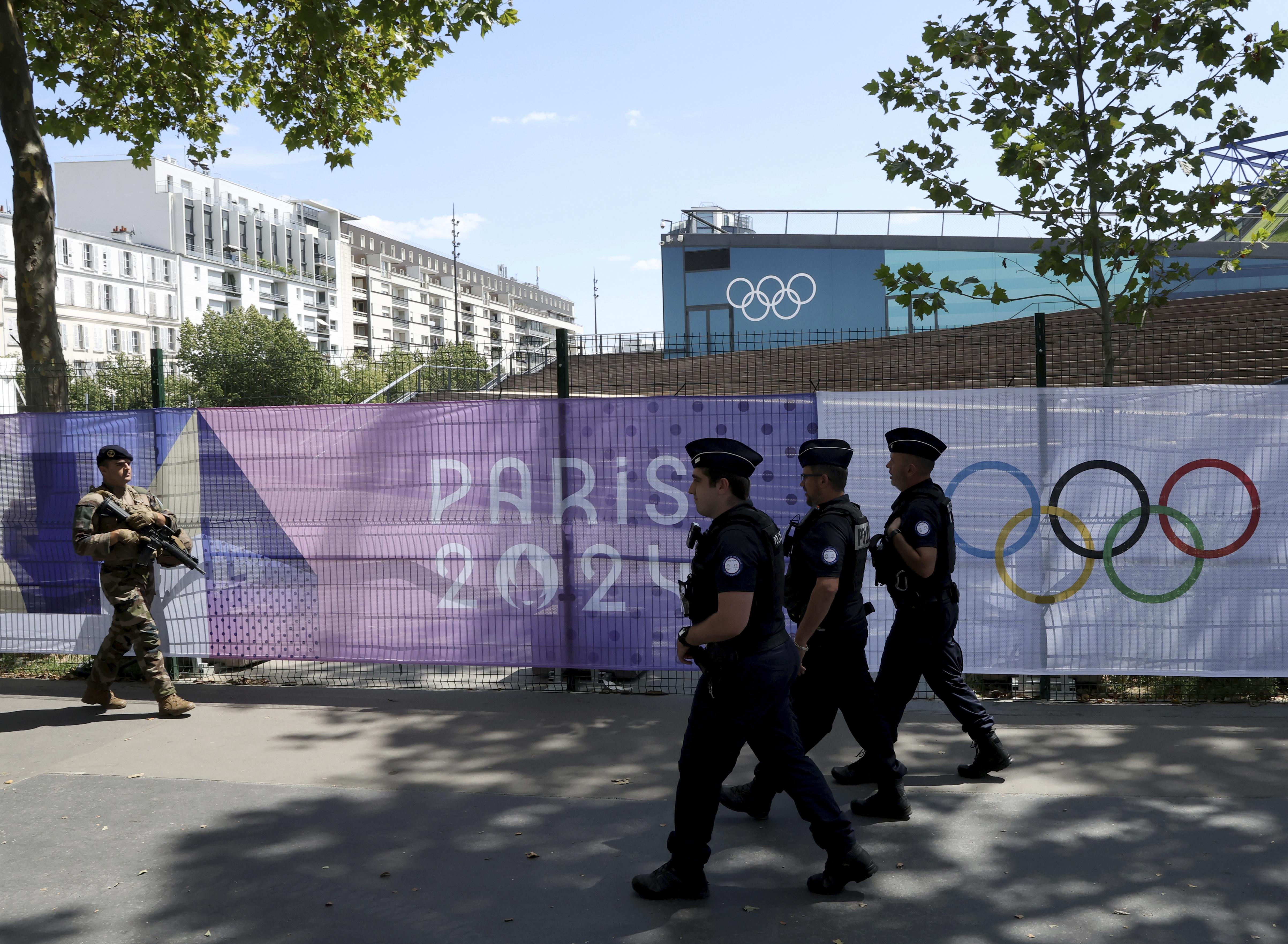 A soldier and police officers patrol by Paris 2024 Olympic banners, before the start of the Paris Olympic games, Wednesday, July 17, 2024, in Paris. (AP Photo/Aurelien Morissard)