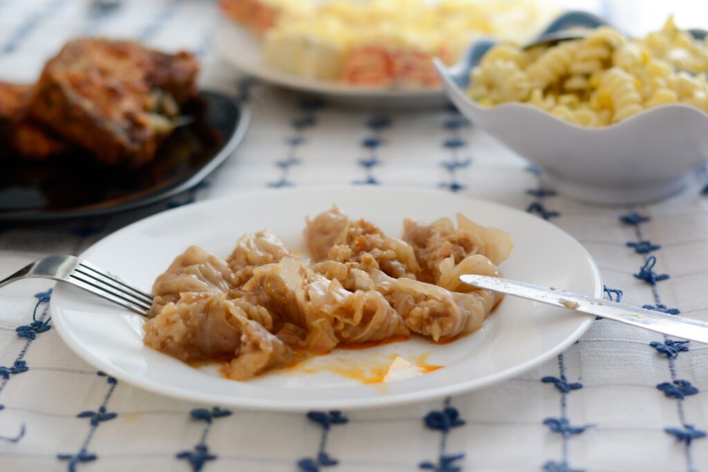 Serbian specialty sarma in the white plate chopped,  with other dishes visible in the background,Image: 335563374, License: Royalty-free, Restrictions: , Model Release: no, Credit line: Dragomir Radovanovic / Panthermedia / Profimedia