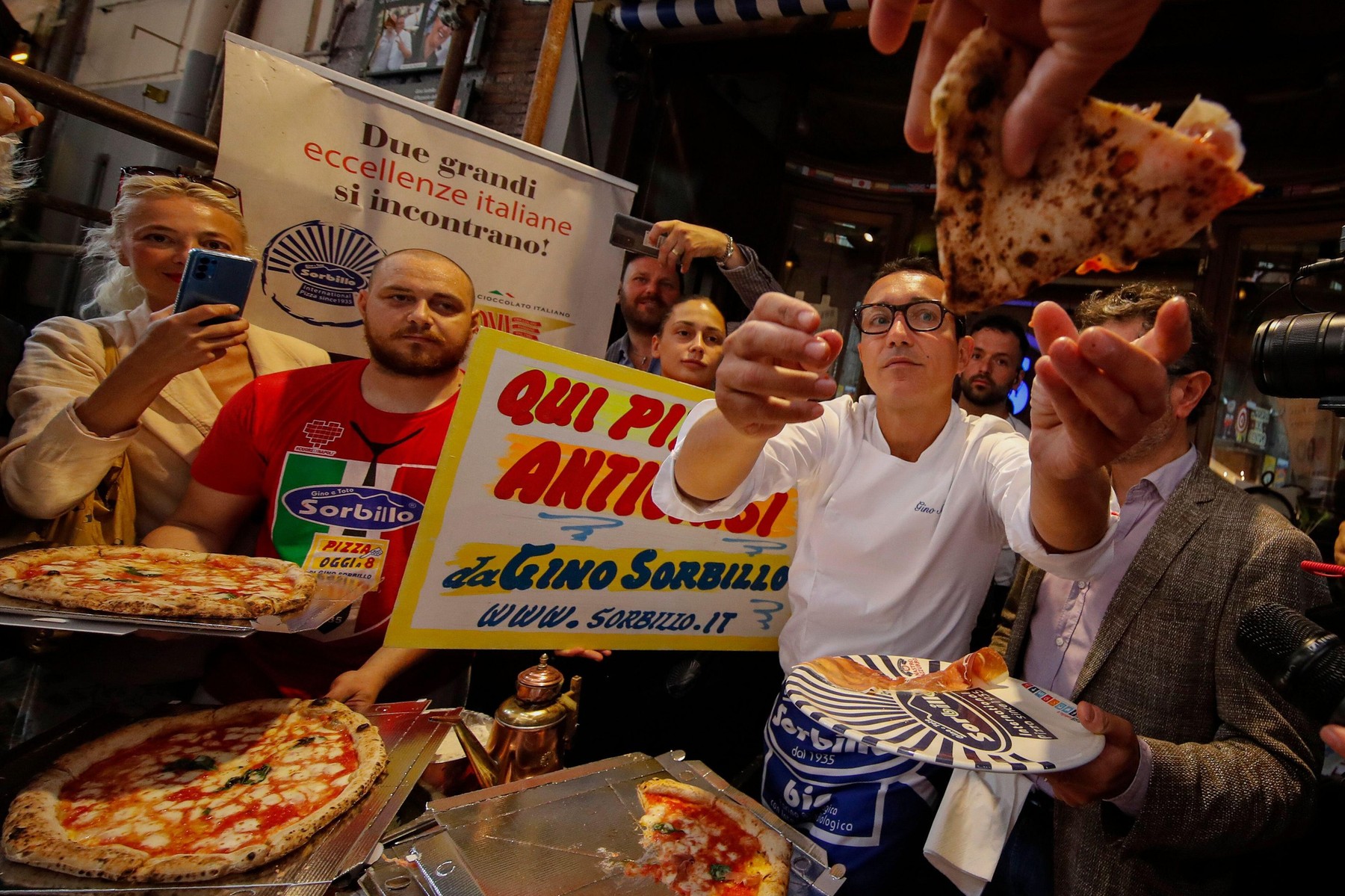 The well-known Neapolitan pizza maker Gino Sorbillo while explaining how to prepare a pizza, and also distributes slices to people and tourists who pass outside the historic location of the pizzeria in via Tribunali. This is after the controversy started