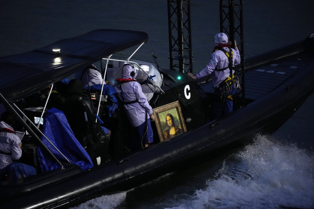 The Mona Lisa painting by Italian artist Leonardo da Vinciin is being taken in a boat on the Seine River in Paris, France, during the opening ceremony of the 2024 Summer Olympics, Friday, July 26, 2024. (AP Photo/Andrew Medichini)