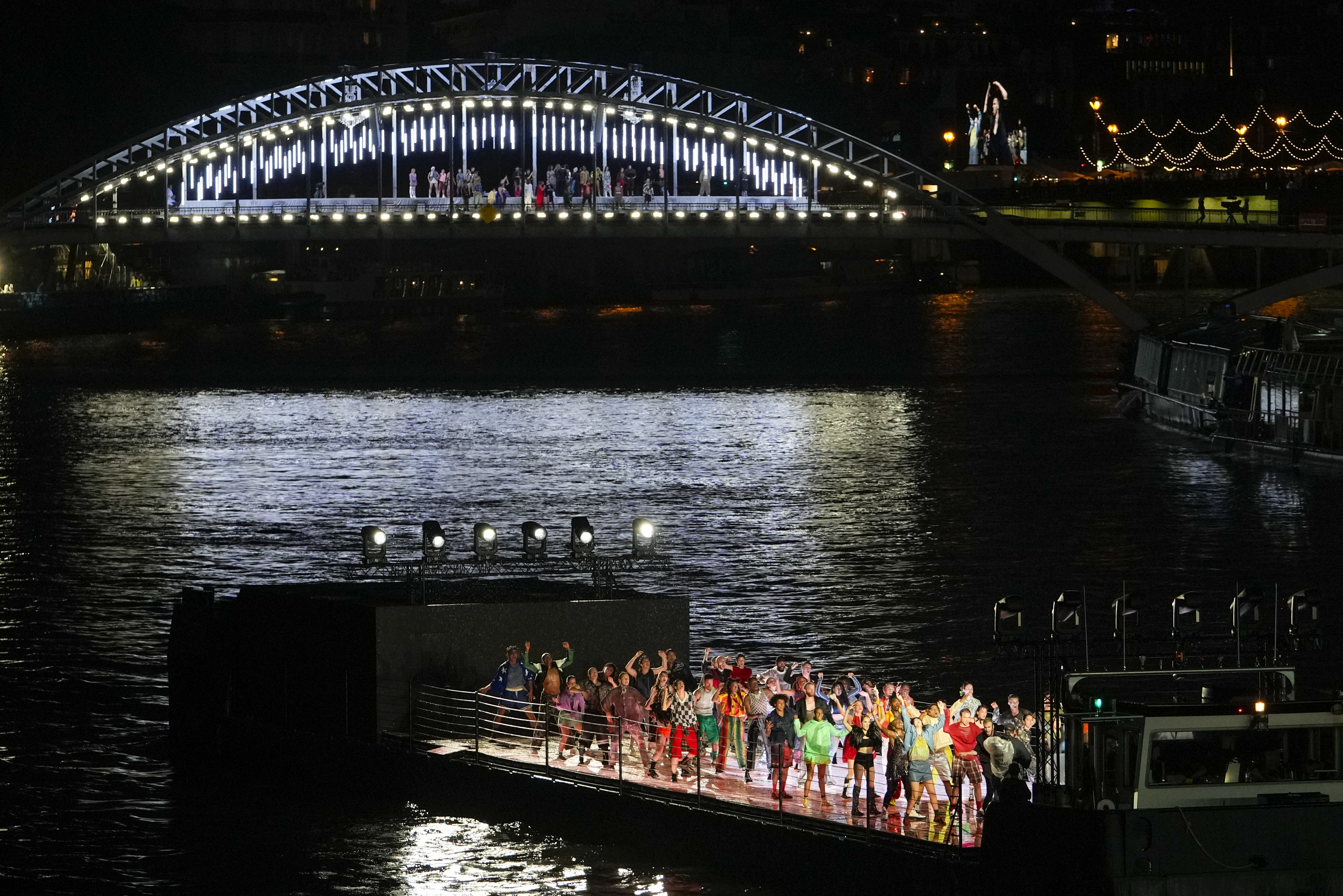 Performers are seen on a barge and a bridge during the opening ceremony of the 2024 Summer Olympics, Friday, July 26, 2024, in Paris, France. (AP Photo/Andy Wong)