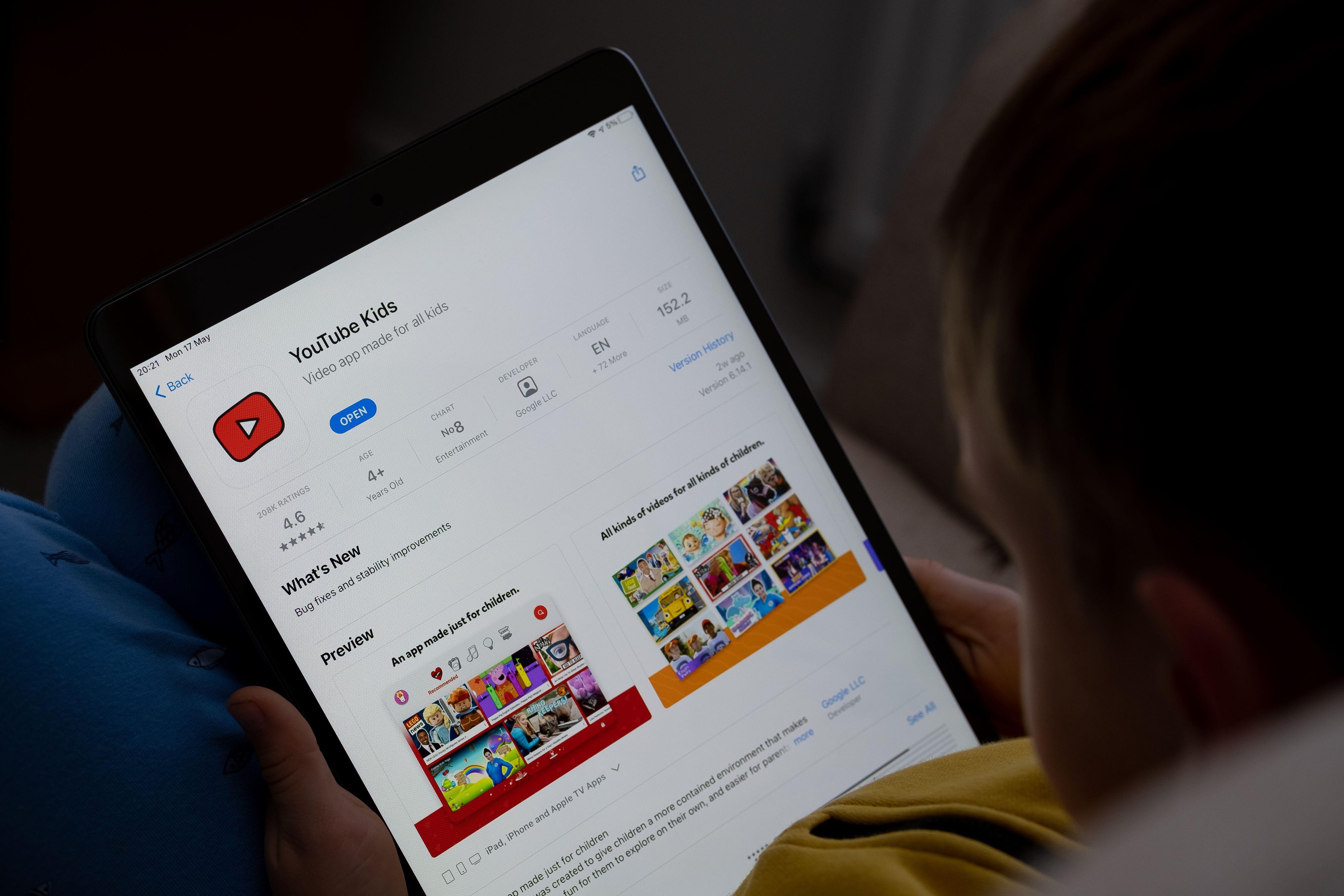 YouTube Kids app seen on the screen of ipad which is in the hands of bored unrecognisable child. Concept. Stafford, United Kingdom, May 18, 2021.