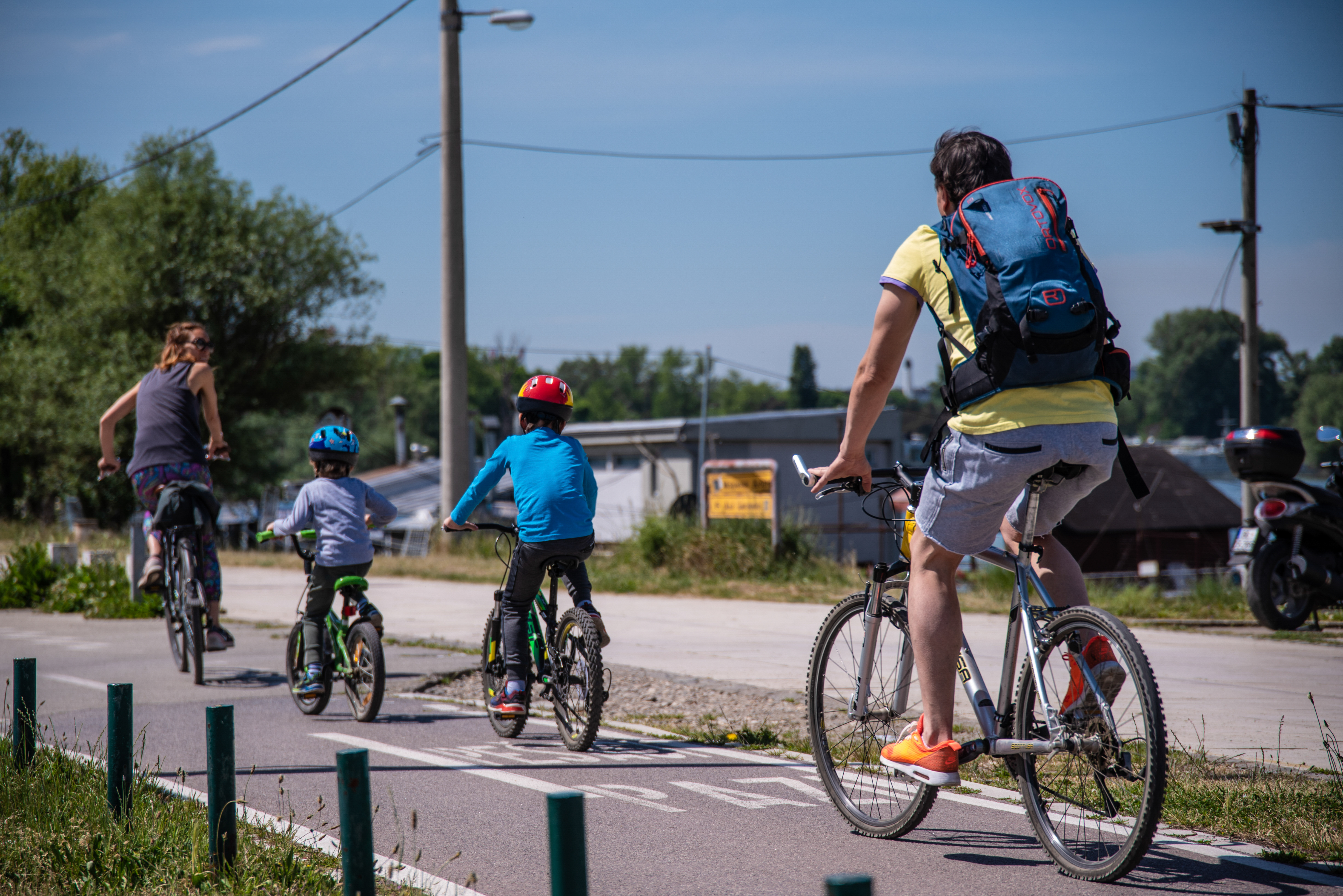 Family,With,Children,Ride,Bicycles,By,River,On,The,First