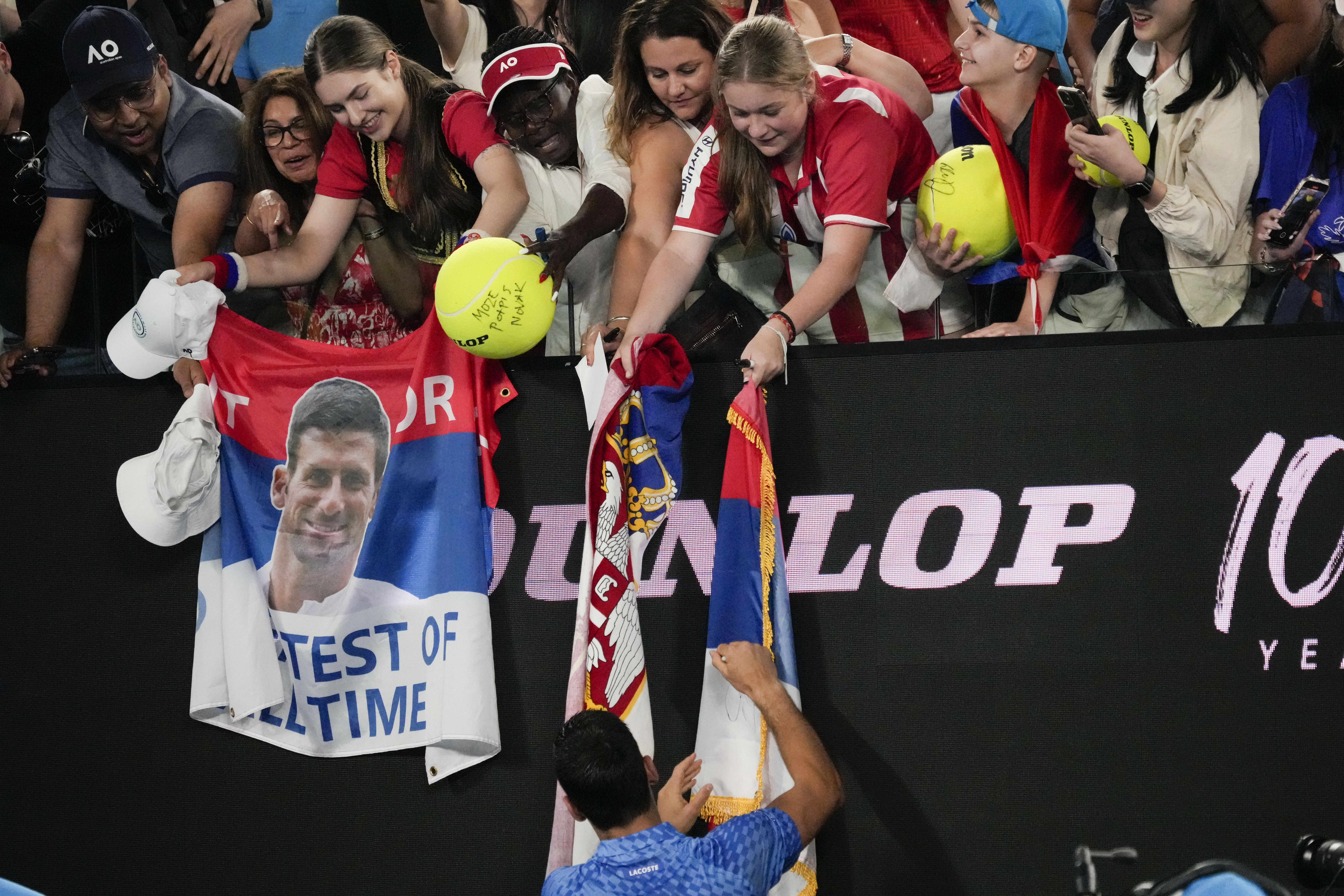 Novak Djokovic of Serbia signs autographs after defeating Roberto Carballes Baena of Spain in their first round match at the Australian Open tennis championship in Melbourne, Australia, Wednesday, Jan. 18, 2023. (AP Photo/Aaron Favila)