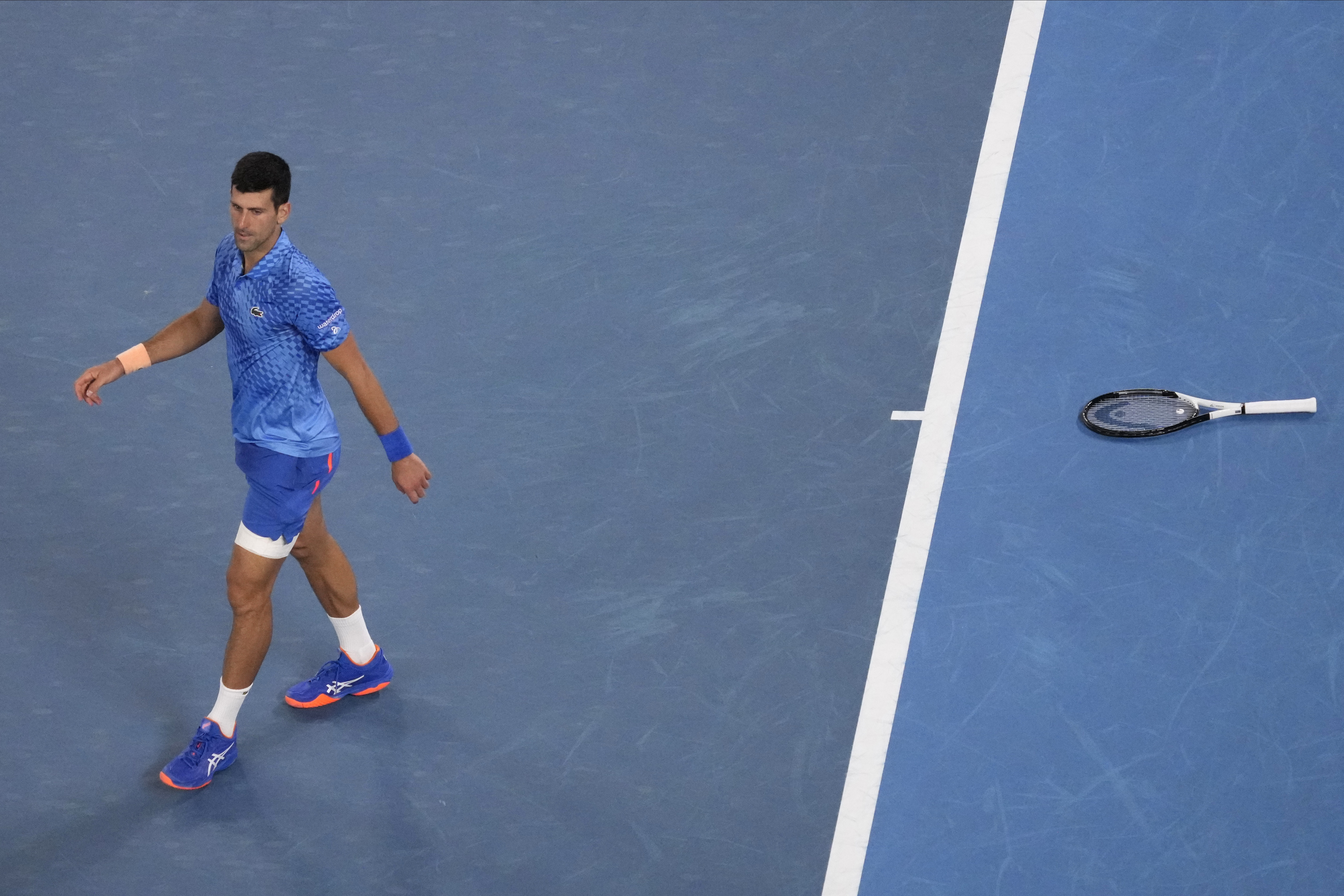Novak Djokovic of Serbia walks away from his racket during his third round match against Grigor Dimitrov of Bulgaria at the Australian Open tennis championship in Melbourne, Australia, Saturday, Jan. 21, 2023. (AP Photo/Dita Alangkara)