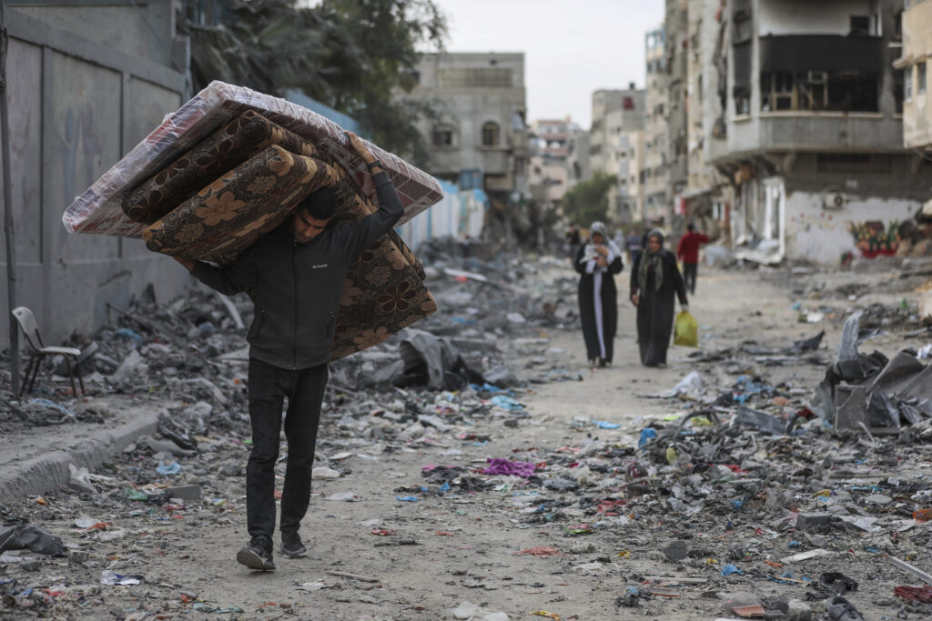 Palestinians walk through destruction in Shati refugee camp on Saturday, Nov. 25, 2023. on the second day of the temporary ceasefire between Hamas and Israel. (AP Photo/Mohammed Hajjar)