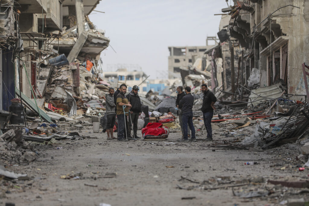 Palestinians stand by a body they pulled out of the destruction in the Shati refugee camp on Saturday, Nov. 25, 2023. on the second day of the temporary ceasefire between Hamas and Israel. (AP Photo/Mohammed Hajjar)