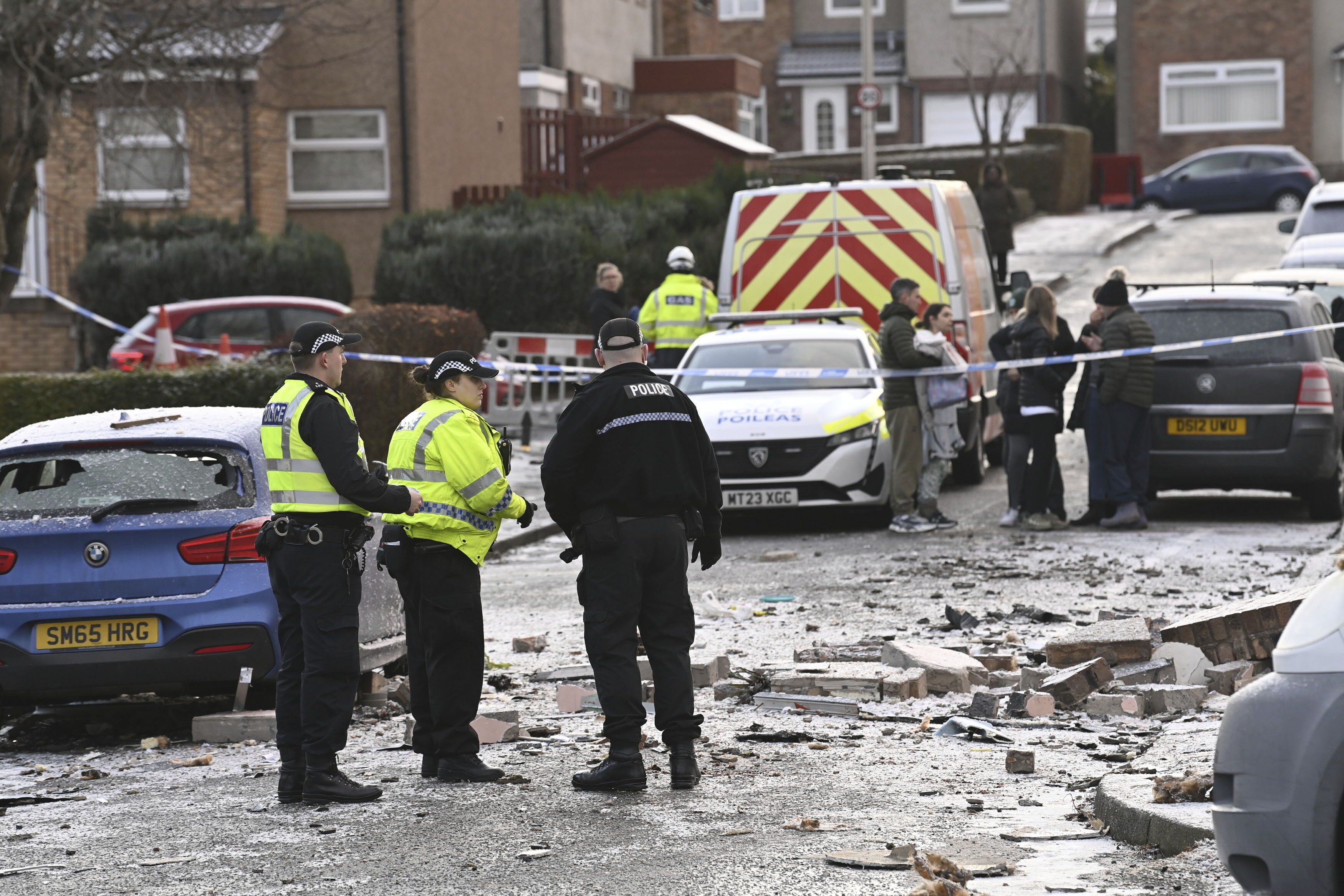 Police officers at the scene on Baberton Mains Avenue, Edinburgh, after an 84-year-old man has died following an explosion at a house on Friday night, Saturday Dec. 2, 2023. (Lesley Martin/PA via AP)