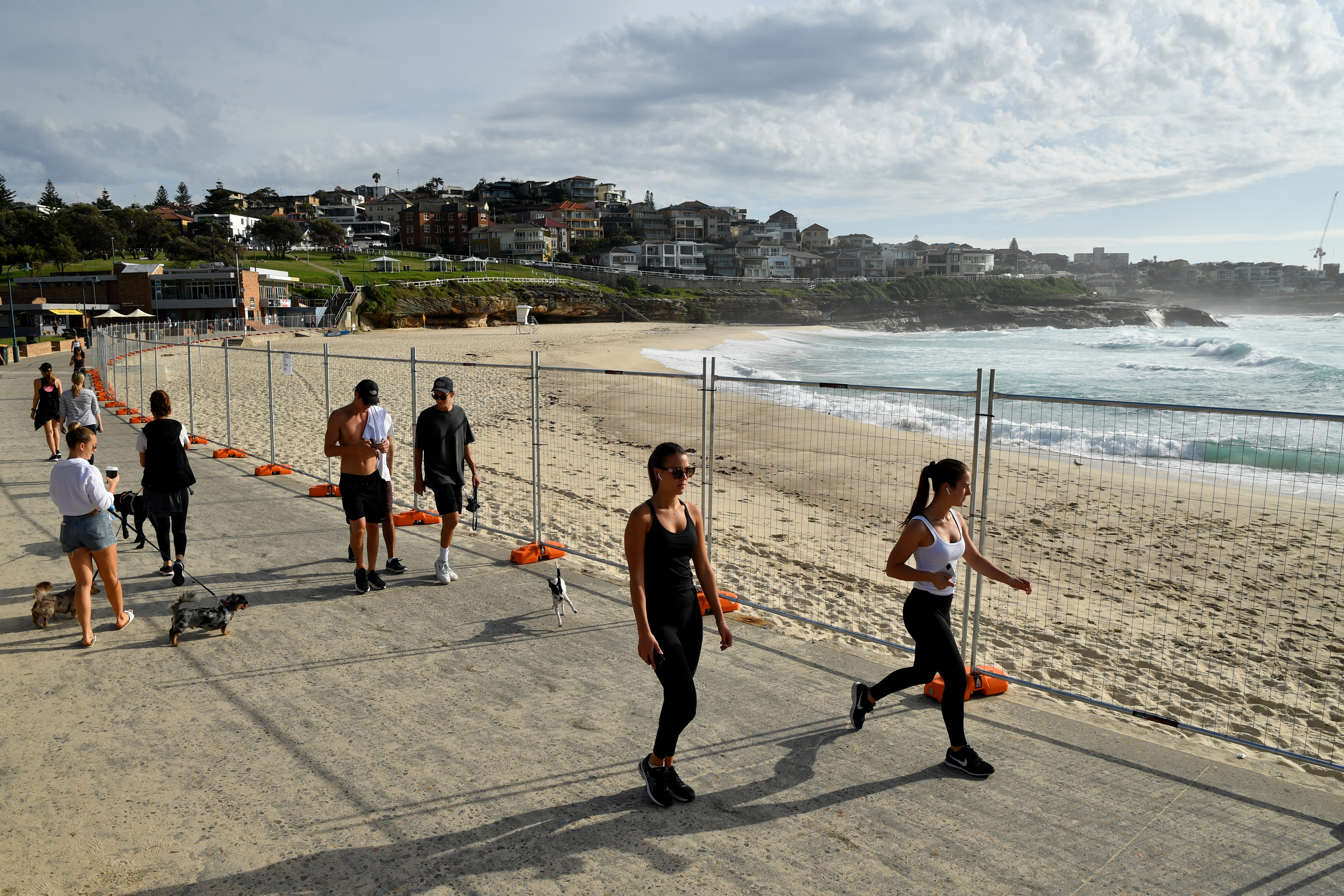 epaselect People walk past fencing at the closed off Bronte Beach in Sydney, Australia, 25 March 2020. A shutdown of non-essential services is in effect in Australia in an attempt to curb the spread of coronavirus amid the ongoing Covid-19 pandemic.