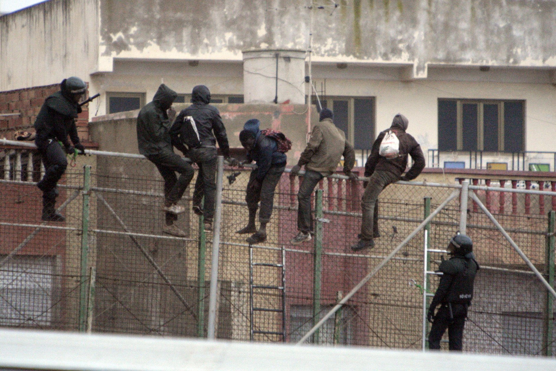 epa04626552 Immigrants sit on the fence at the border between Morocco and Melilla, Spanish enclave on the north of Africa, as they try to enter the country on 19 February 2015.  EPA/F.G. GUERRERO