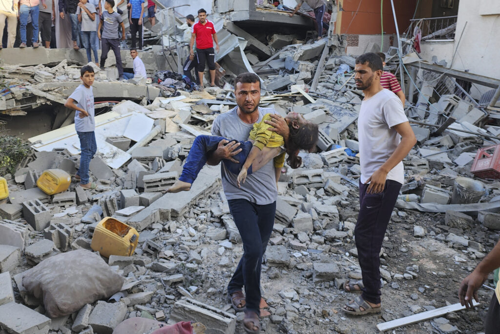 Palestinian carries a child killed in an airstrike on the buildings of Abu Asad family in Deir el-Balah, southern Gaza Strip, Saturday, Oct. 21, 2023. (AP Photo/Hassan Eslaiah)