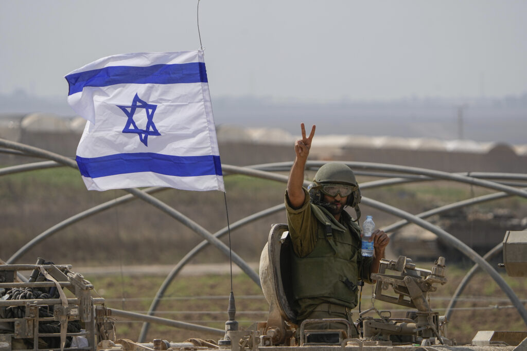An Israeli soldier flashes a V-sign from an armoured personnel carrier (APC) as they head towards the Gaza Strip border in southern Israel, Saturday, Oct. 14, 2023. (AP Photo/Ariel Schalit)