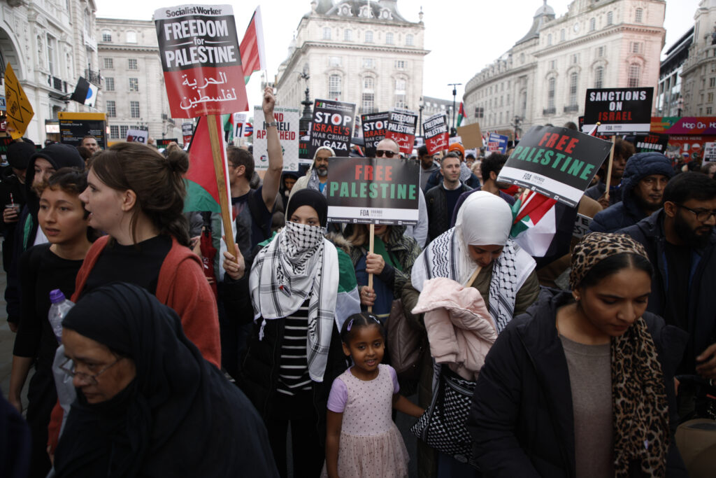 Demonstrators hold up flags and placards during a pro Palestinian demonstration in London, Saturday, Oct. 21, 2023. (AP Photo/David Cliff)