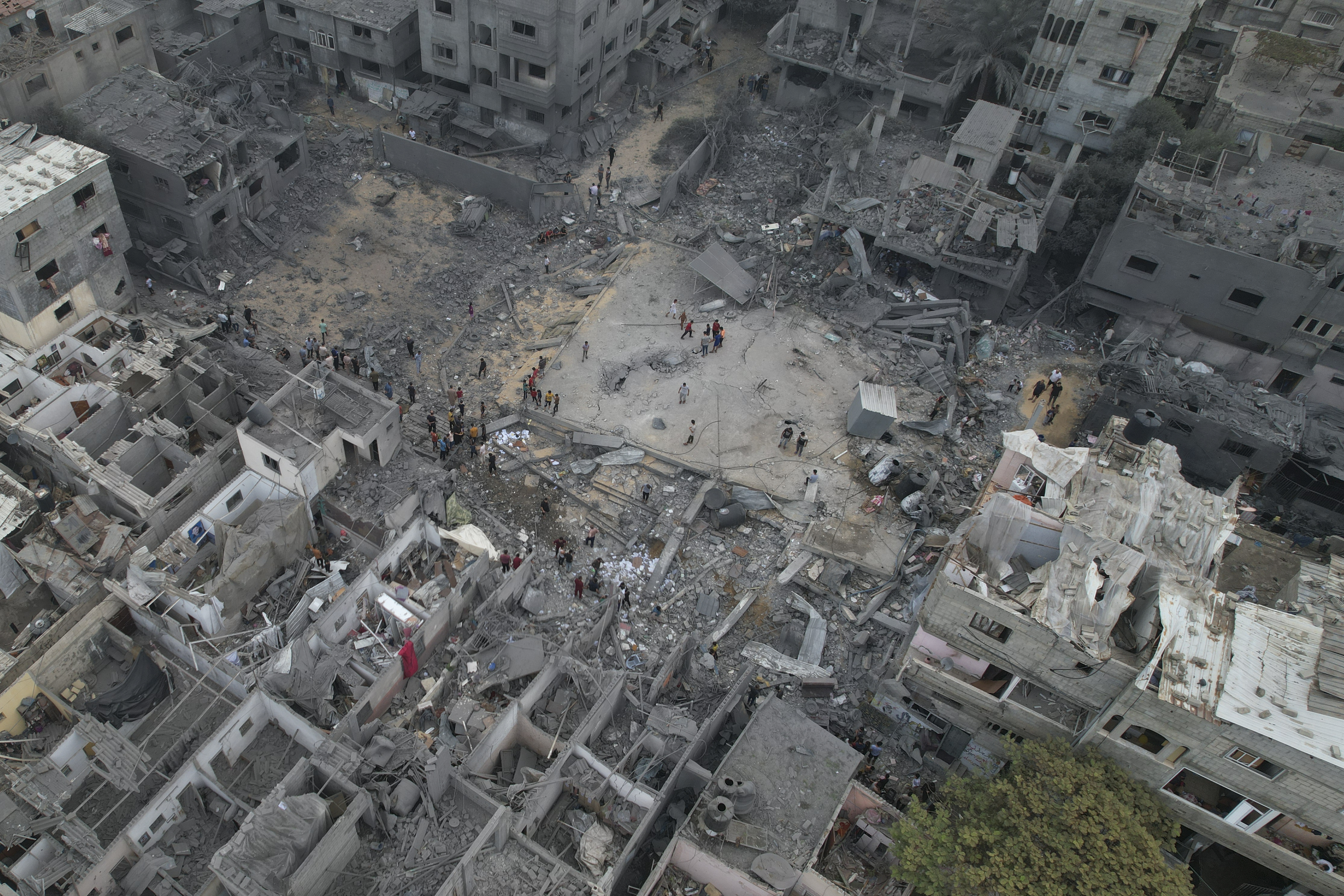 Palestinians walk about buildings destroyed in the Israeli bombardment in the Nusseirat refugee camp in the Gaza Strip on Sunday, Oct. 29, 2023. (AP Photo/Hatem Moussa)