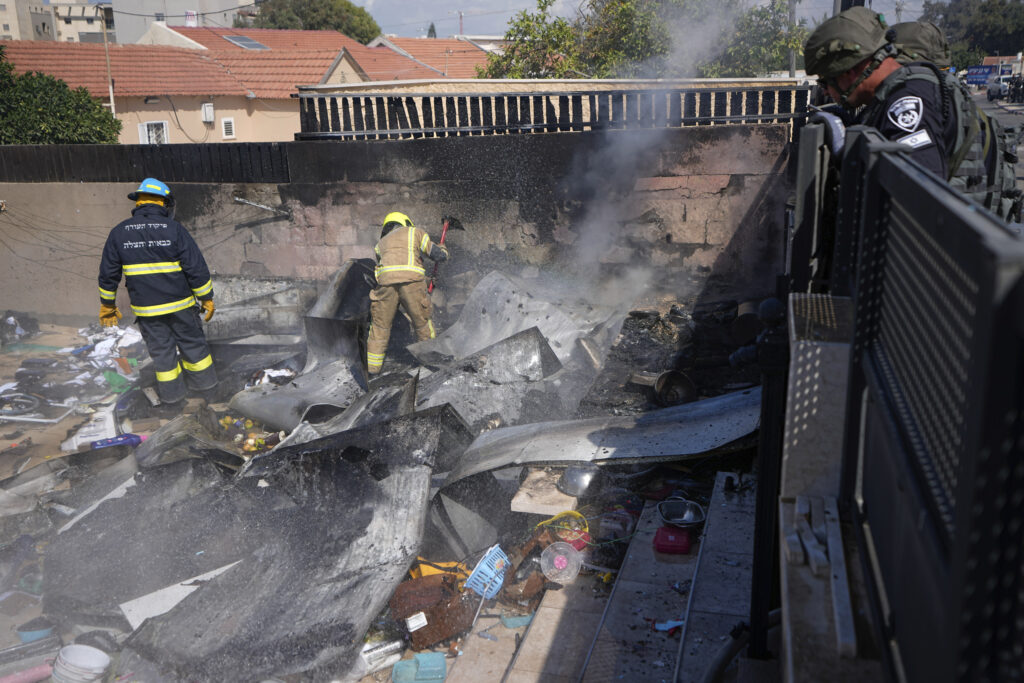 Israeli firefighters extinguish fire at a site struck by a rocket fired from the Gaza Strip, in the southern Israeli town of Sderot, Sunday, Oct. 15, 2023. (AP Photo/Ariel Schalit)