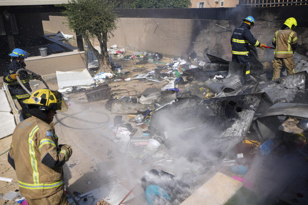 Israeli firefighters extinguish fire at a site struck by a rocket fired from the Gaza Strip, in the southern Israeli town of Sderot, Sunday, Oct. 15, 2023. (AP Photo/Ariel Schalit)