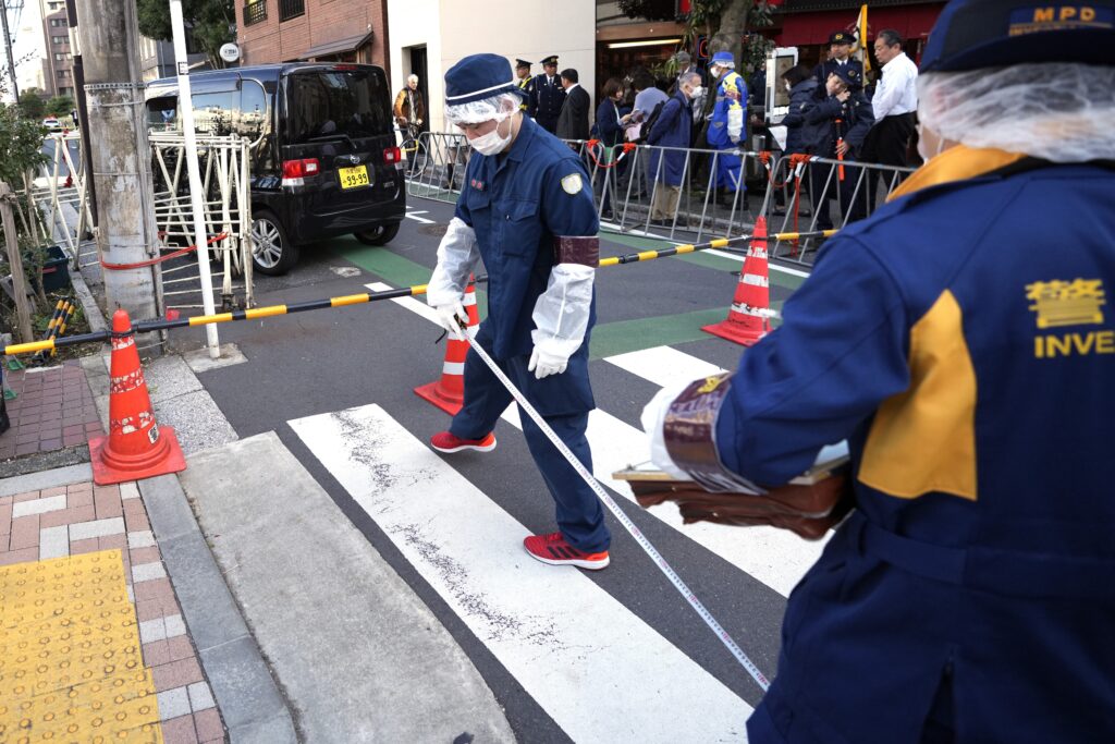 Police officers work at the scene of a car crash after the car, rear, crashed into a temporary barricade near the Israeli Embassy in Tokyo Thursday, Nov. 16, 2023. Police arrested the driver, according to reports. (AP Photo/Eugene Hoshiko)