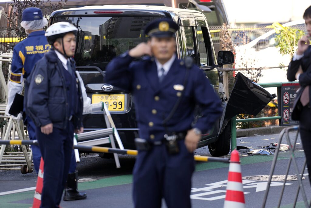 Police officers exam a car, rear, which crashed into a temporary barricade near the Israeli Embassy in Tokyo Thursday, Nov. 16, 2023. Police arrested the driver, according to reports. (AP Photo/Eugene Hoshiko)