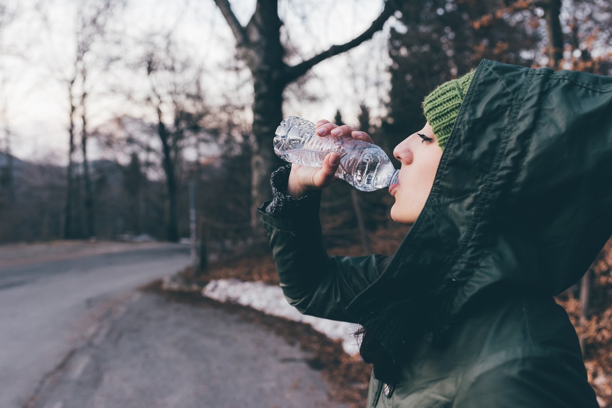 Female hiker drinking water on forest roadside, Monte San Primo, Italy