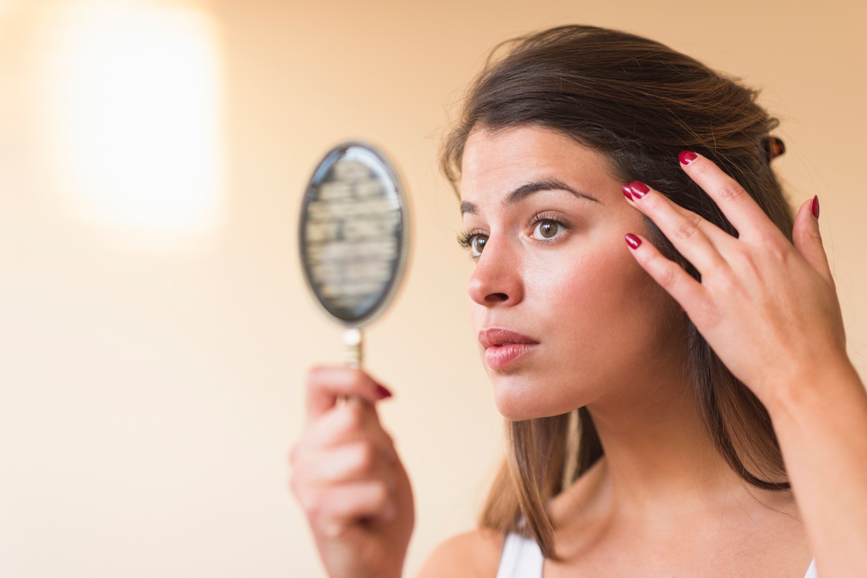 Young woman looking in hand mirror