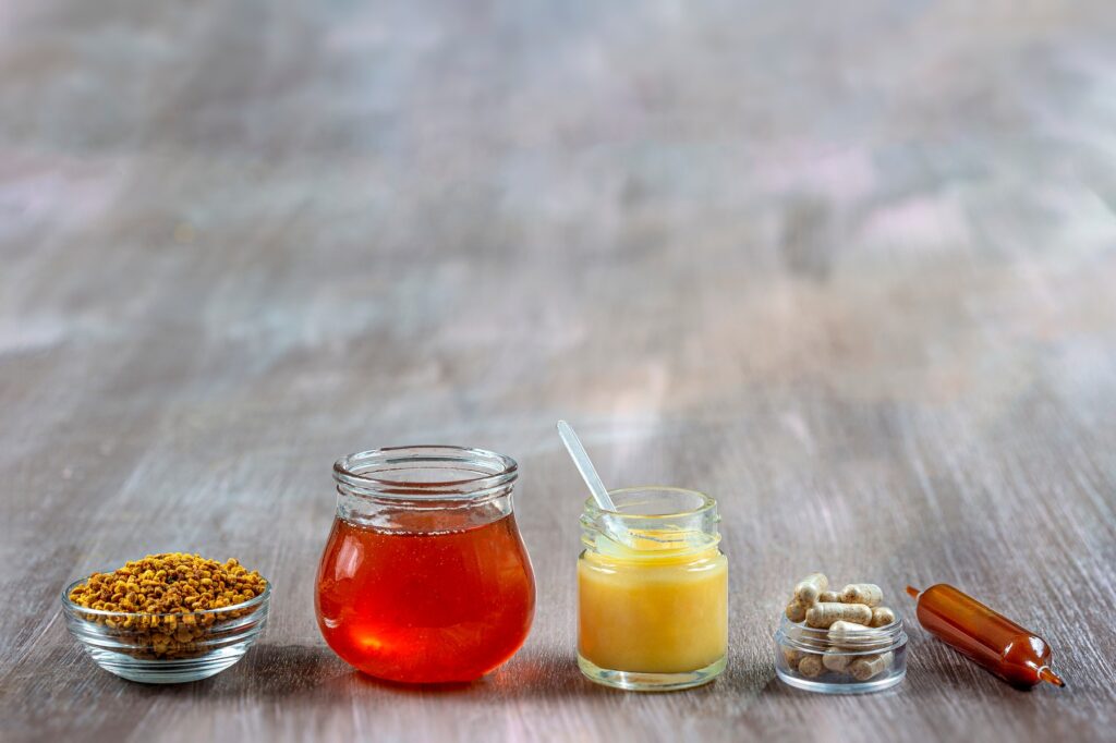 Honey, royal jelly, pollen and food supplement capsules lined up in the foreground.,Image: 713607115, License: Rights-managed, Restrictions: , Model Release: no, Credit line: CHASSENET / BSIP / Universal images group / Profimedia