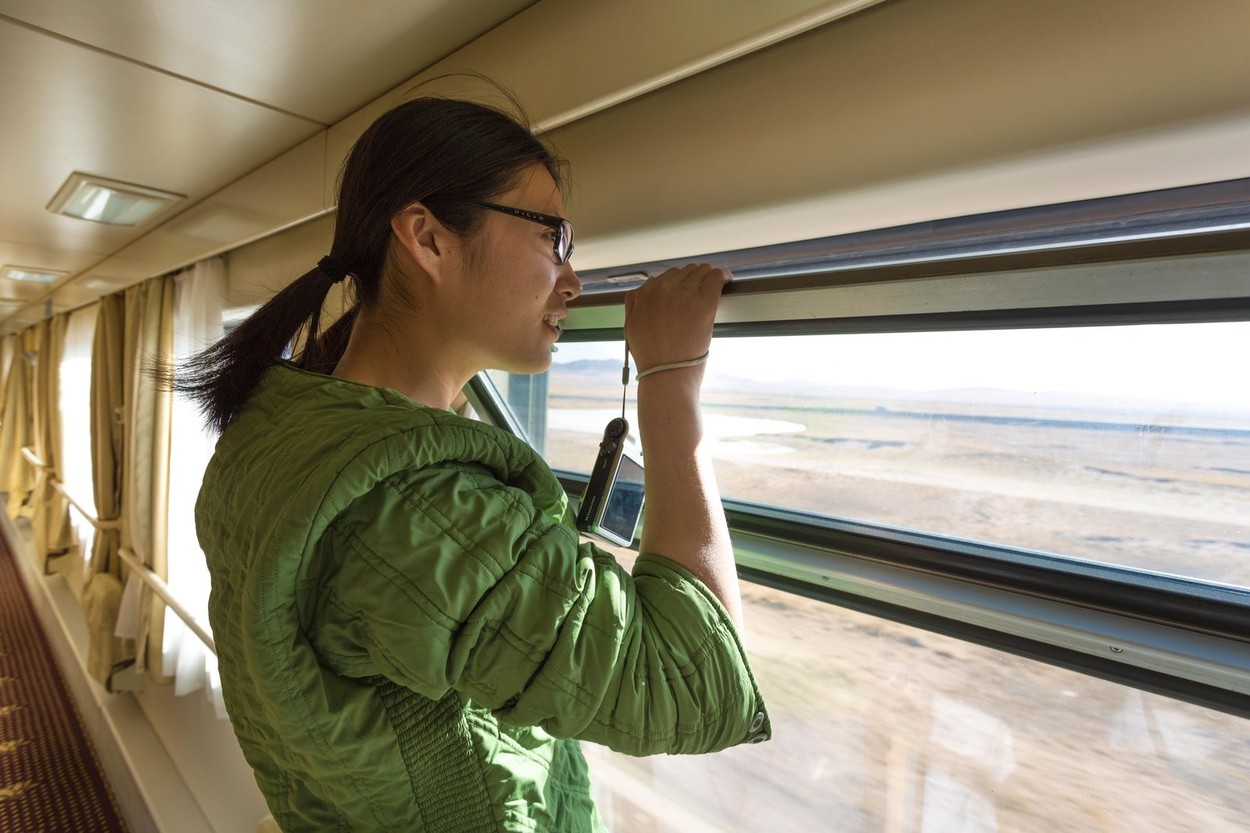 Chinese young woman looking by an open window in train