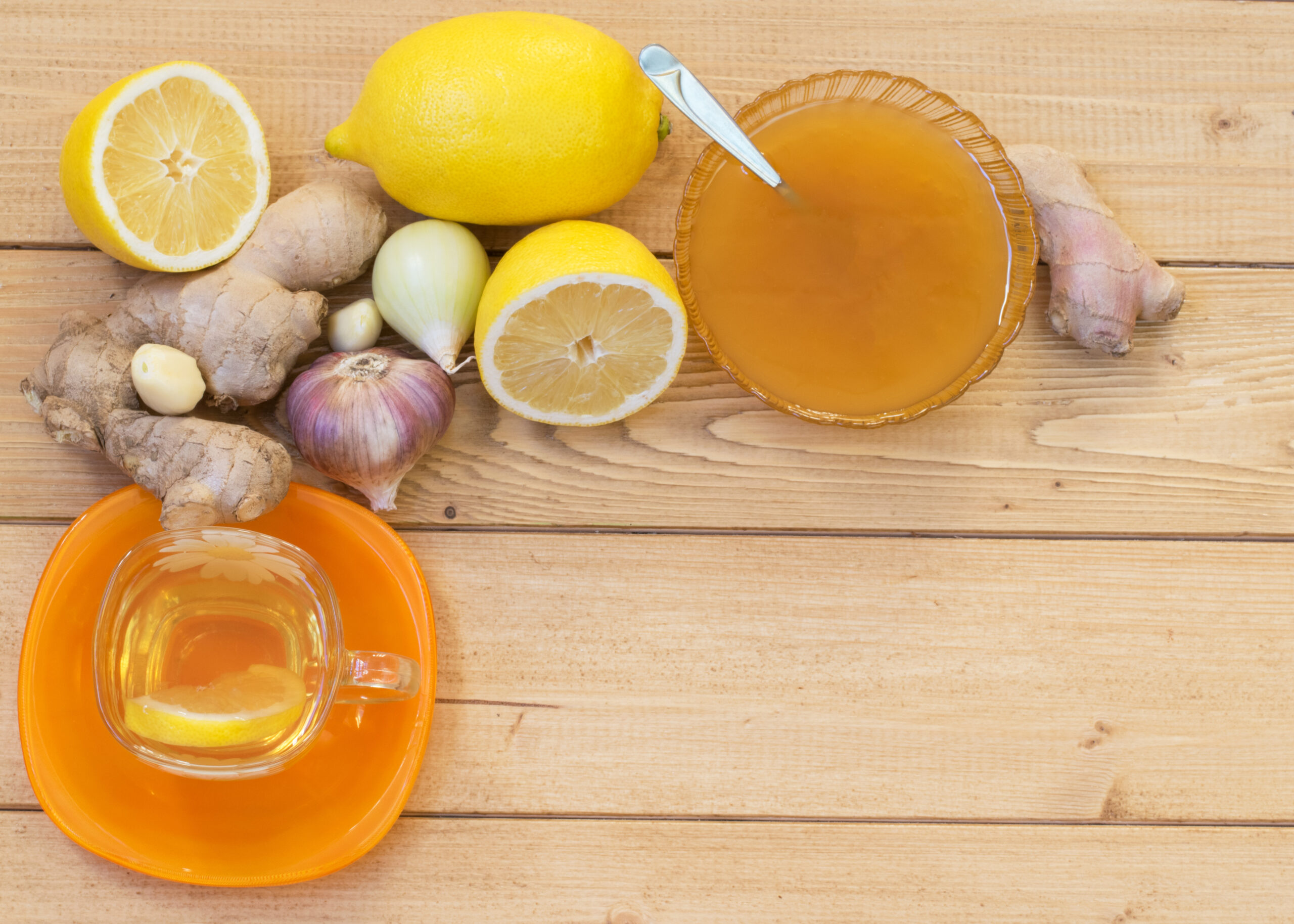 The root of ginger, lemon, garlic, onion and honey on wooden table. The concept of treatment with natural products.