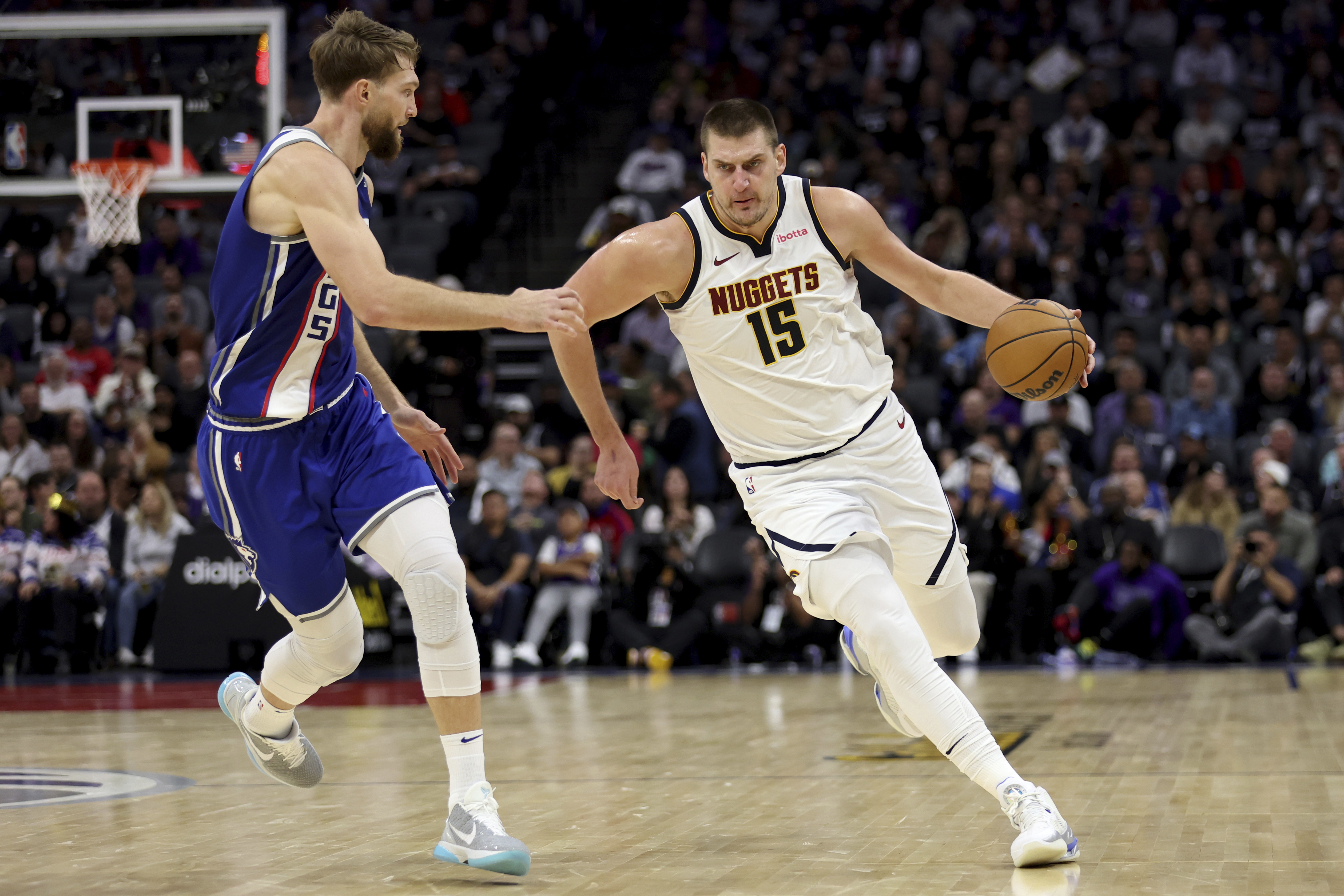 Denver Nuggets center Nikola Jokic (15) drives to the basket against Sacramento Kings forward Domantas Sabonis, left, during the first half of an NBA basketball game in Sacramento, Calif, Saturday, Dec. 2, 2023. (AP Photo/Jed Jacobsohn)