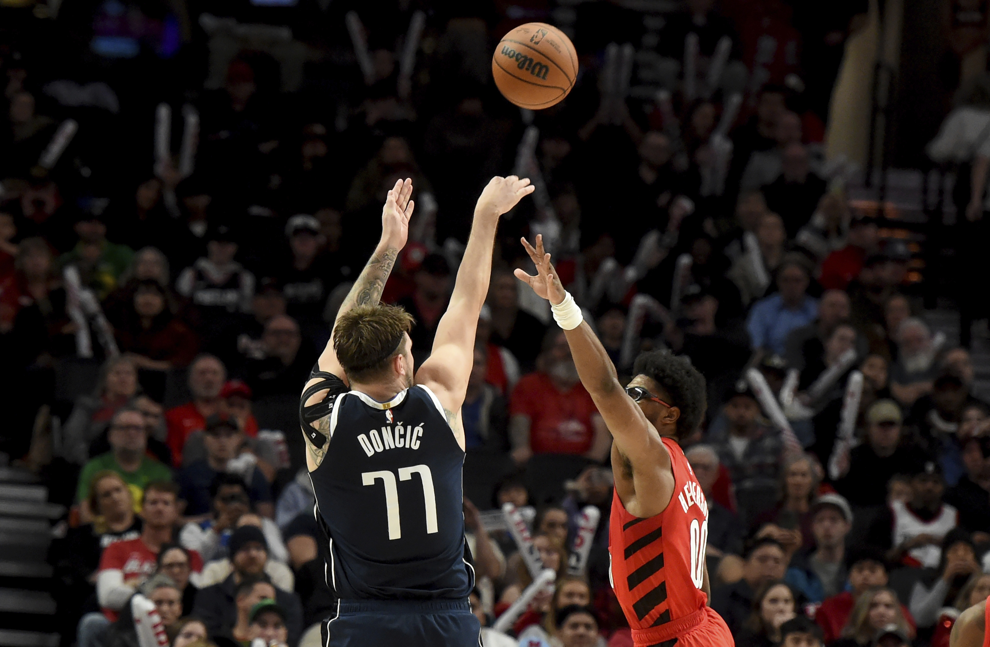 Dallas Mavericks guard Luka Doncic (77) hits a shot over Portland Trail Blazers guard Scoot Henderson during the second half of an NBA basketball game in Portland, Ore., Saturday, Dec. 16, 2023. (AP Photo/Steve Dykes)