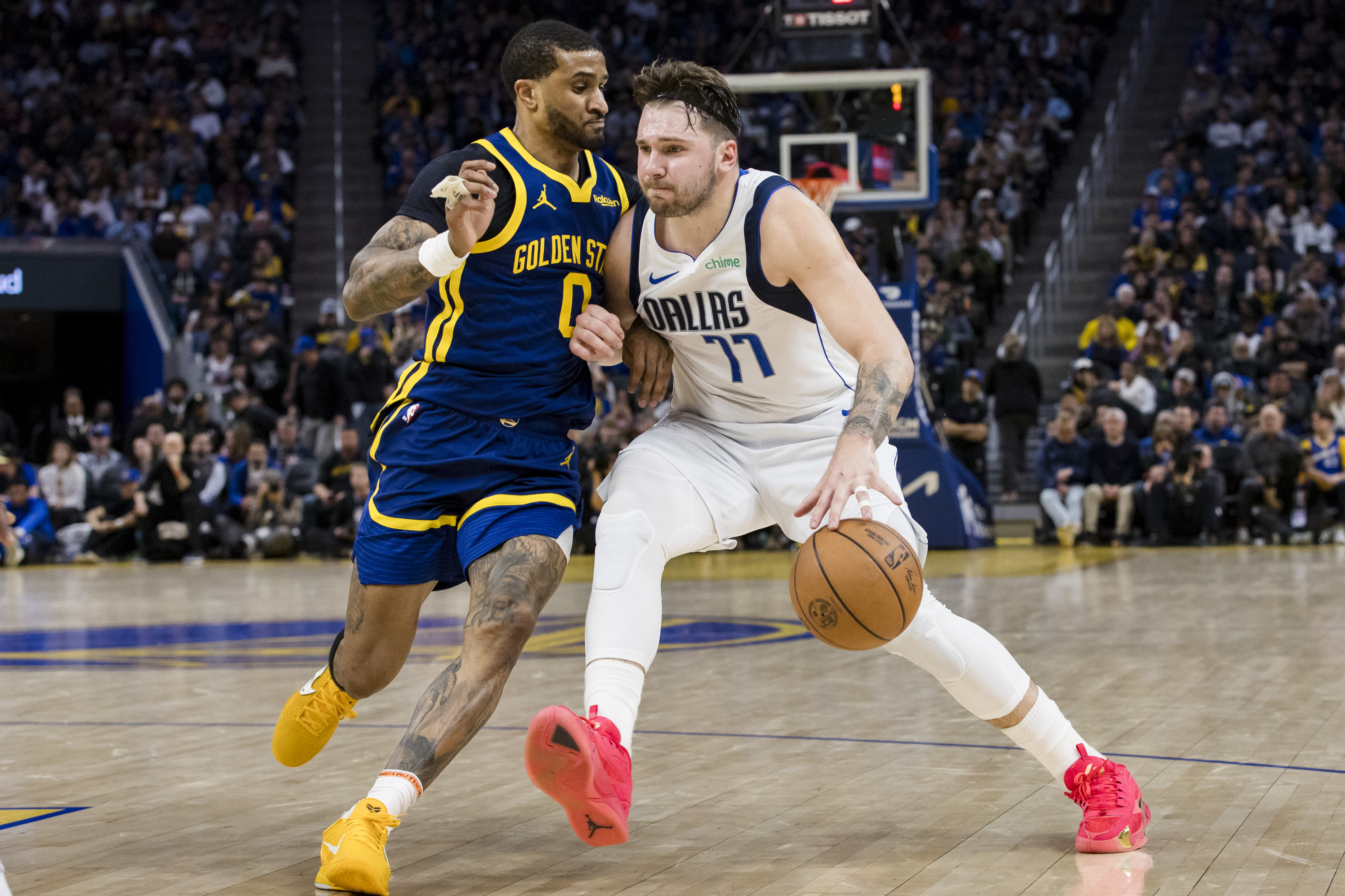 Golden State Warriors guard Gary Payton II (0) defends against Dallas Mavericks guard Luka Doncic (77) during the second half of an NBA basketball game in San Francisco, Saturday, Dec. 30, 2023. (AP Photo/John Hefti)
