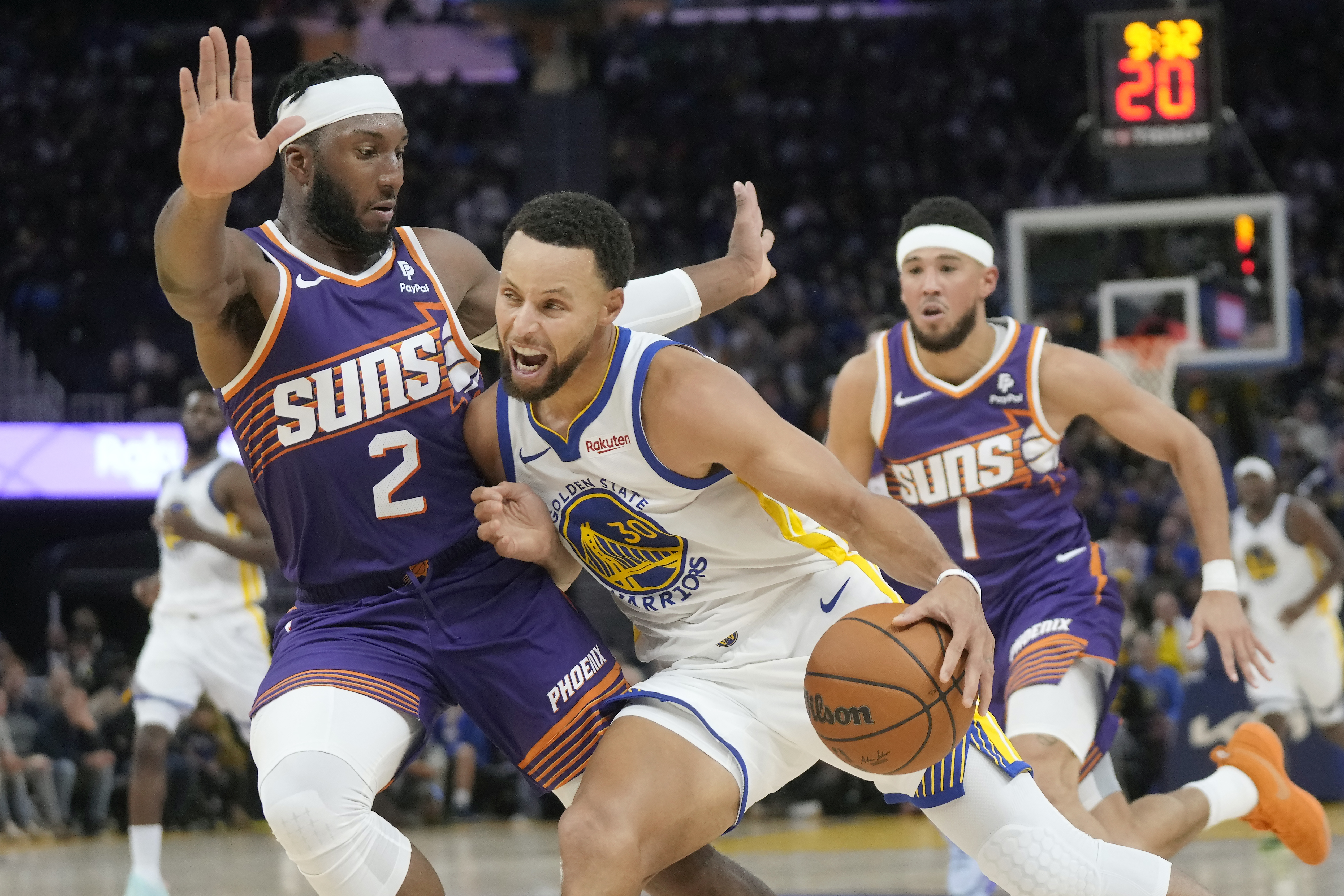 Golden State Warriors guard Stephen Curry (30) drives to the basket between Phoenix Suns forward Josh Okogie (2) and guard Devin Booker (1) during the second half of an NBA basketball game in San Francisco, Tuesday, Oct. 24, 2023. (AP Photo/Jeff Chiu)