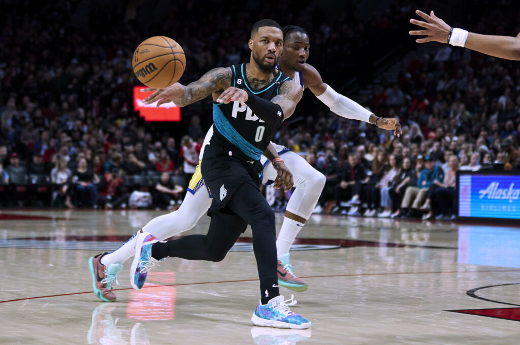 Portland Trail Blazers guard Damian Lillard (0) passes the ball away from Golden State Warriors forward Jonathan Kuminga during the second half of an NBA basketball game in Portland, Ore., Wednesday, Feb. 8, 2023. (AP Photo/Craig Mitchelldyer)