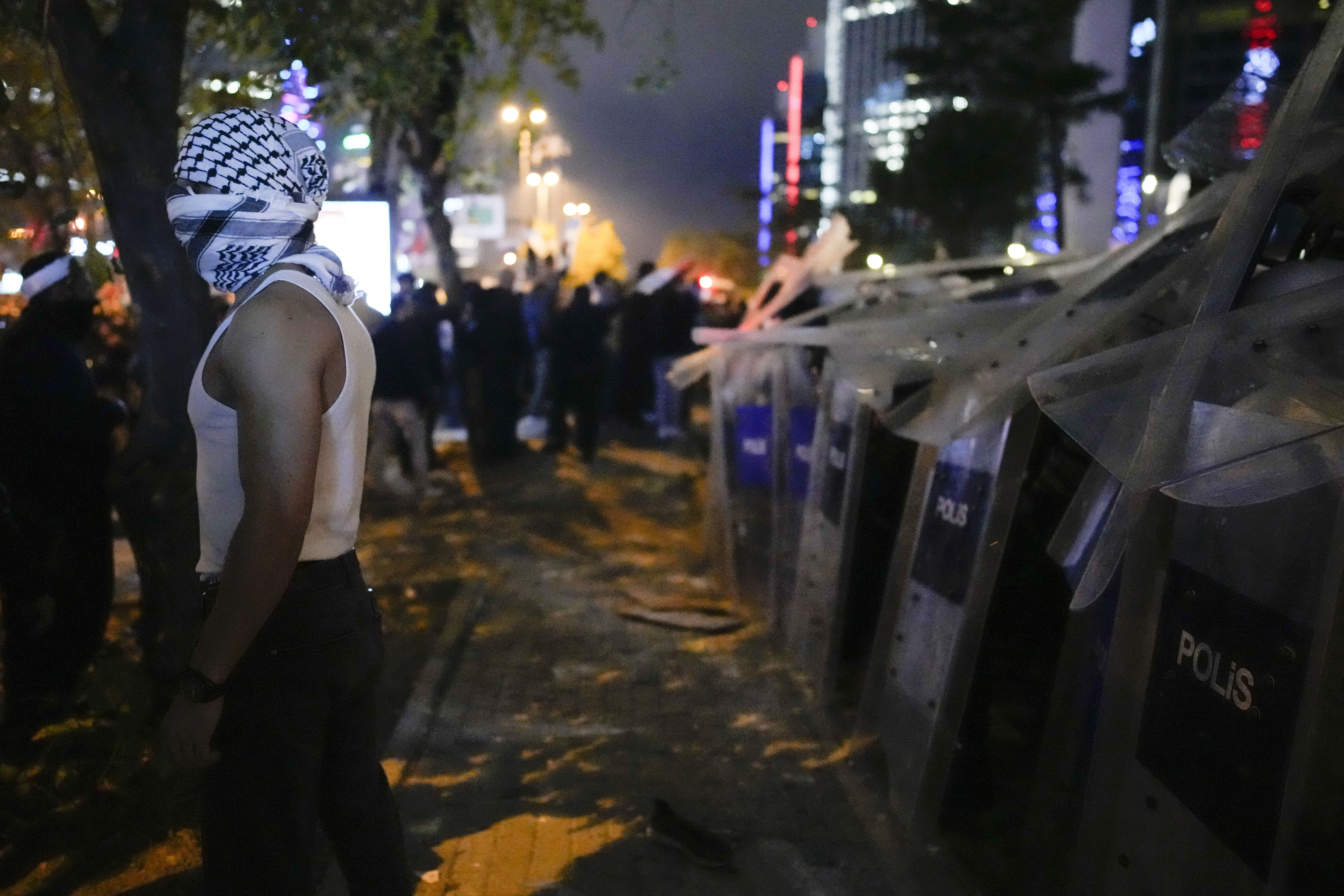A man stands next to anti riot policemen during a protest to show solidarity with Palestinians outside the Israeli consulate in Istanbul, Turkey, Tuesday, Oct. 17, 2023.  (AP Photo/Emrah Gurel)