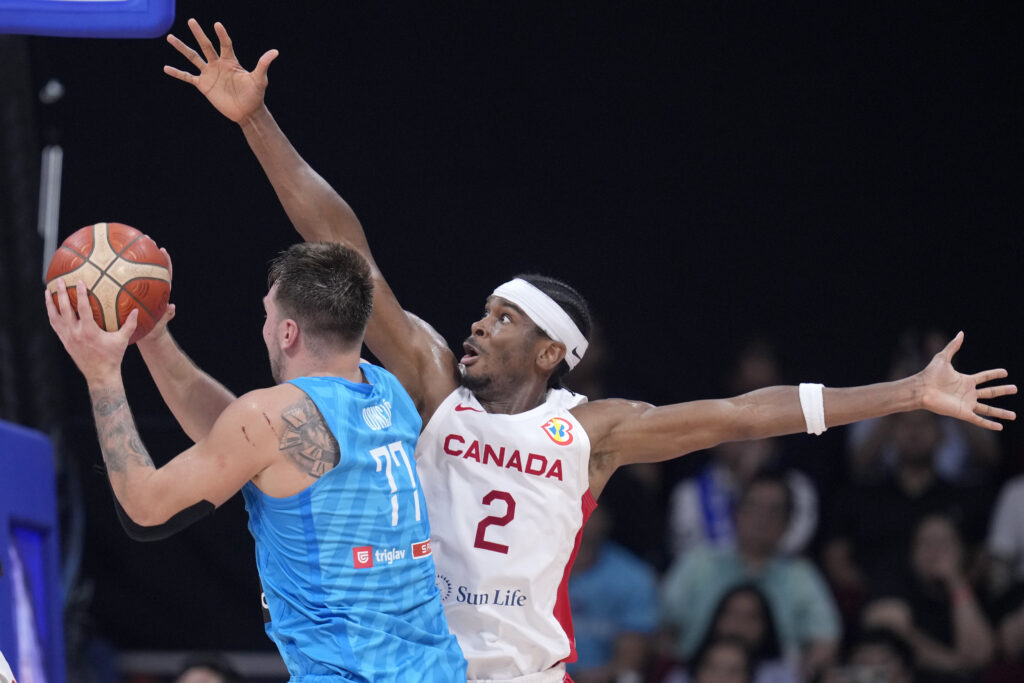 Slovenia's Luka Doncic (77) heads to the basket past Canada's Shai Gilgeous-Alexander (2) during the second half of a Basketball World Cup quarterfinal game in Manila, Philippines, Wednesday, Sept. 6, 2023. (AP Photo/Michael Conroy)