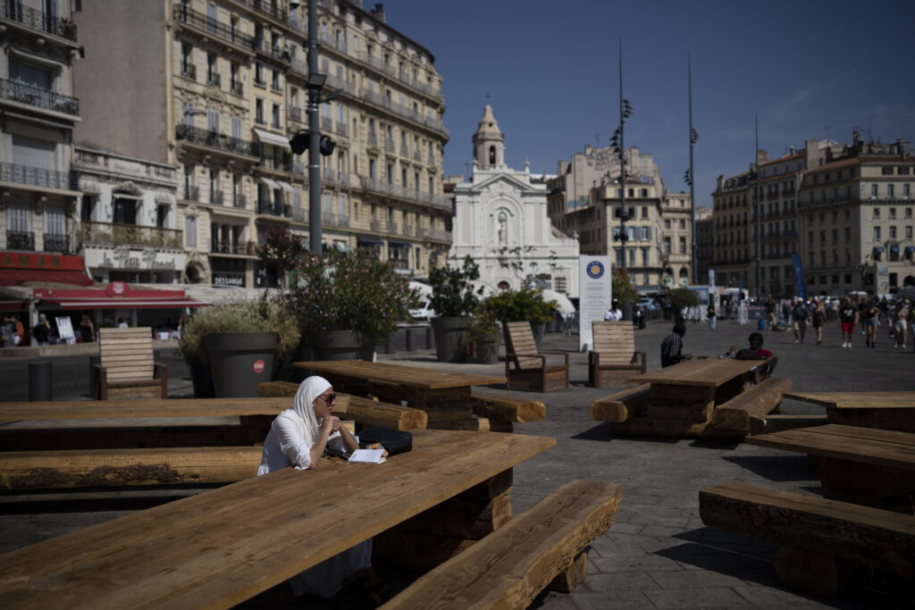 A woman sits on a bench in high temperatures in Marseille, southern France, Saturday, Aug. 19, 2023. (AP Photo/Daniel Cole)