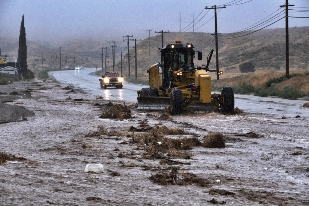 A plow clears debris along a flooded Sierra Highway in Palmdale, Calif., as Tropical Storm Hilary moves through the area on Sunday, Aug. 20, 2023. (AP Photo/Richard Vogel)