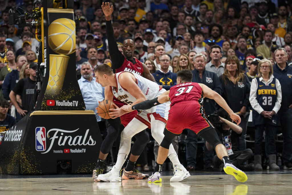 Denver Nuggets center Nikola Jokic, center, is defended by Miami Heat center Bam Adebayo, rear, and guard Max Strus (31) during the first half of Game 5 of basketball's NBA Finals, Monday, June 12, 2023, in Denver. (AP Photo/Jack Dempsey)