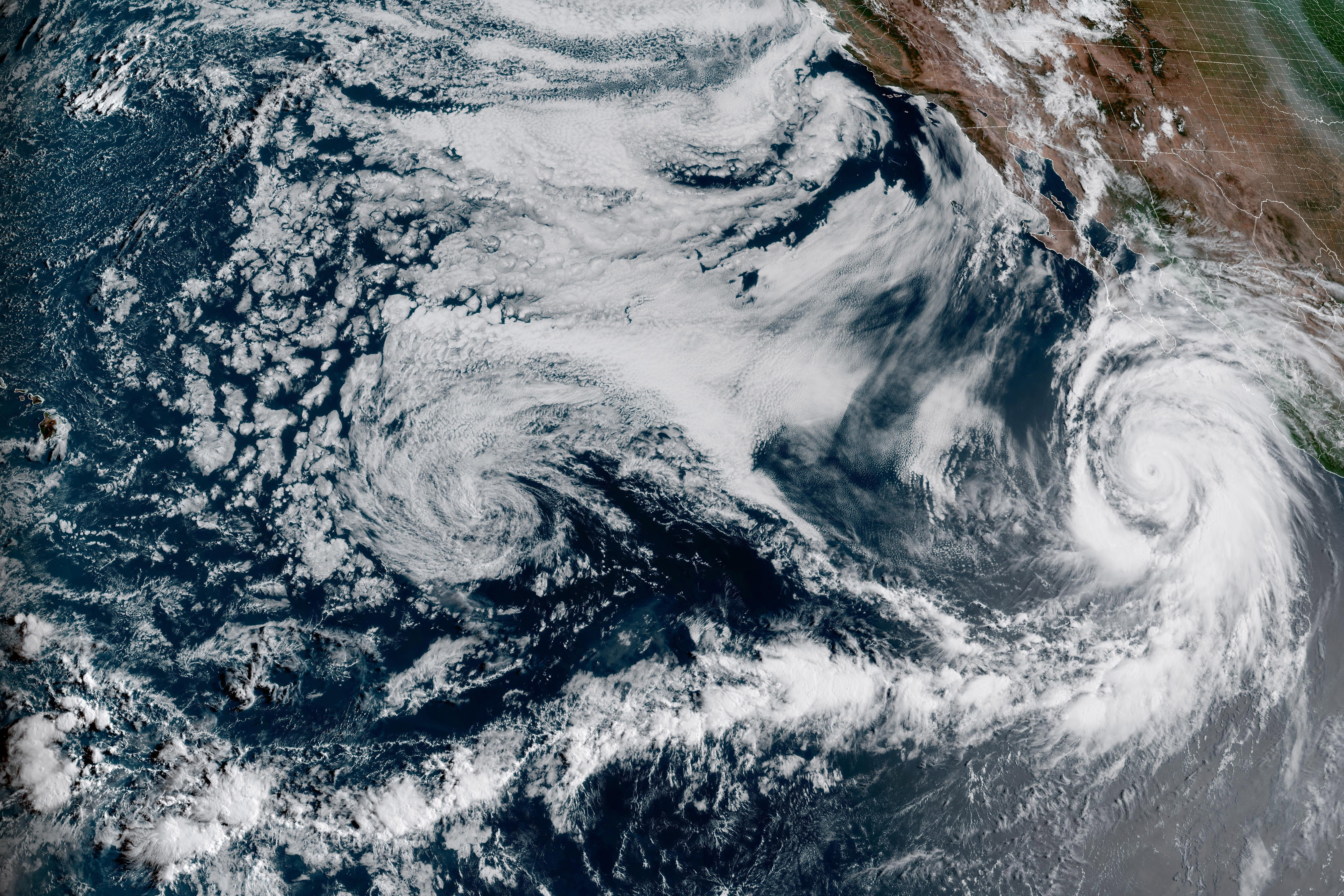 This Friday, Aug. 18, 2023, 1:10 p.m. EDT satellite image provided by the National Oceanic and Atmospheric Administration shows Hurricane Hilary, right, off Mexico’s Pacific coast.  (NOAA via AP)