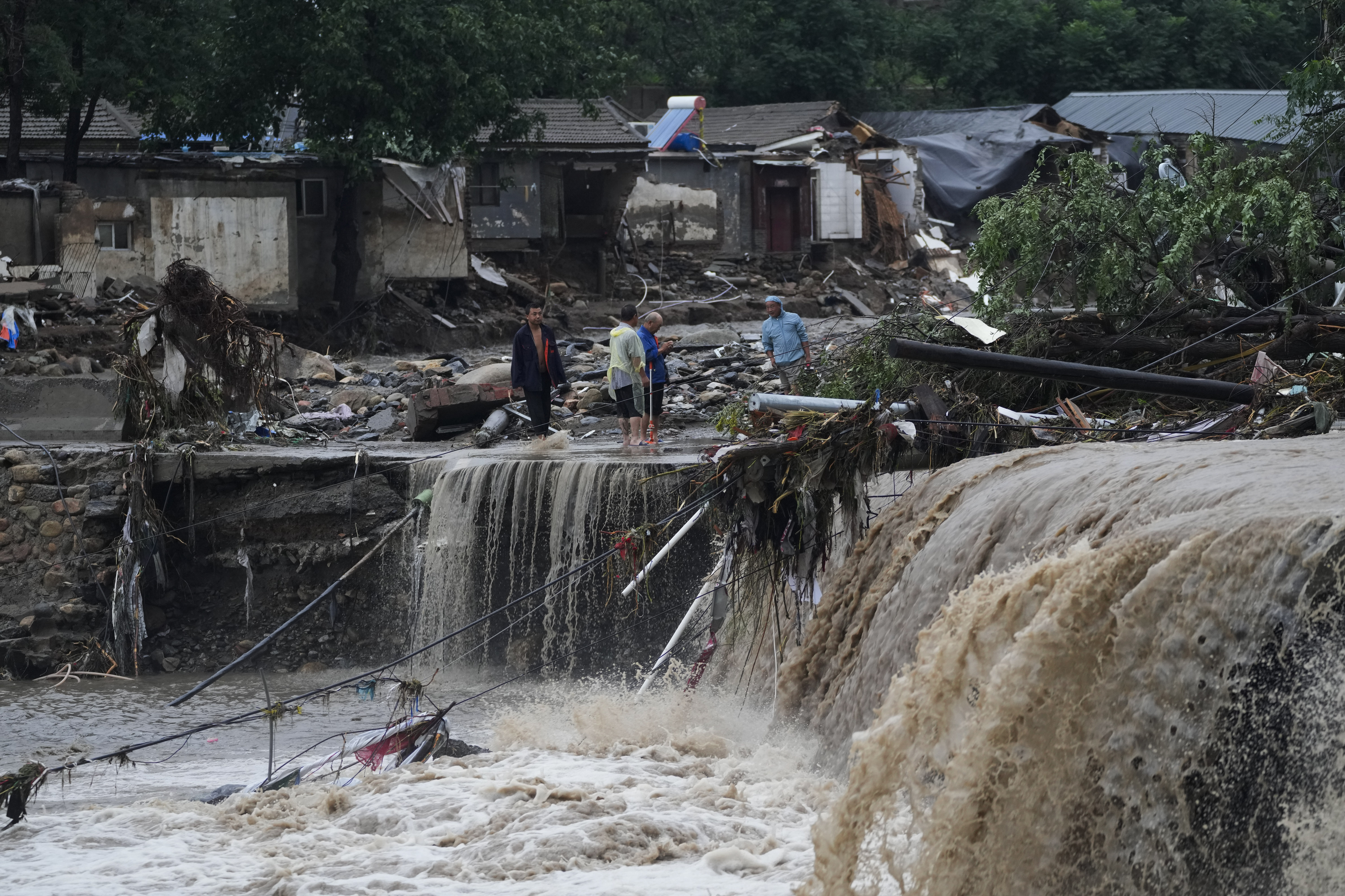 Villagers gather near a village damaged by floodwaters in the Mentougou District as continuous rain fall triggers alerts in Beijing, Monday, July 31, 2023. (AP Photo/Andy Wong)