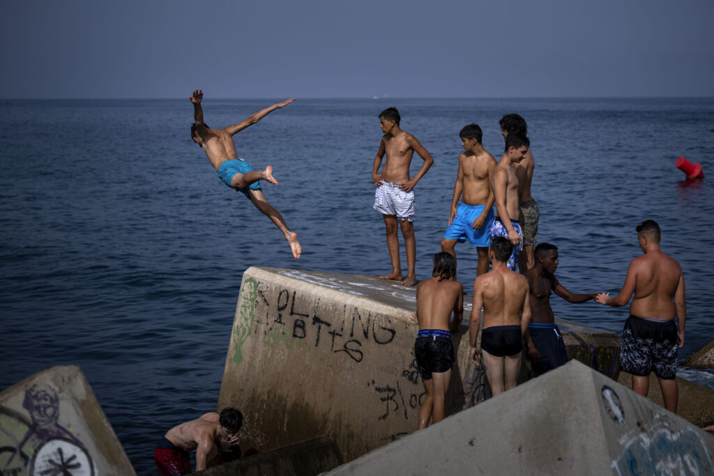 A man jumps into the sea on a breakwater in Barcelona, Spain, Wednesday, July 12, 2023. More than 10 of Spain's regions are on red alert for the second day of the latest heat wave, with temperatures topping 40 degrees Celsius. (AP Photo/Emilio Morenatti)