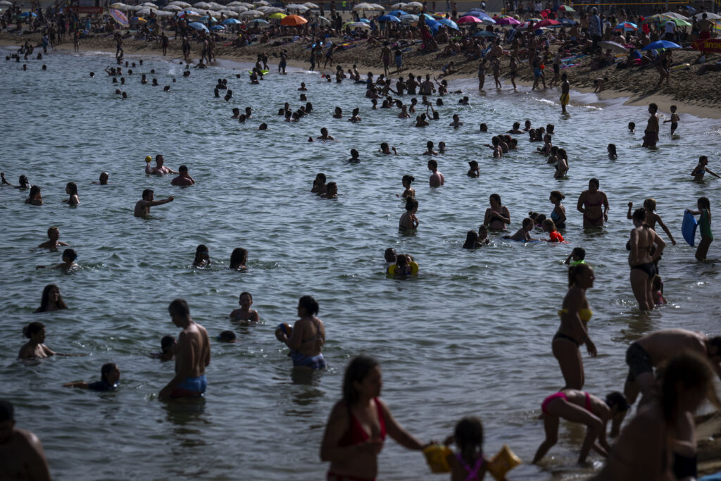 People cool off on a beach in Barcelona, Spain, Wednesday, July 12, 2023. More than 10 of Spain's regions are on red alert for the second day of the latest heat wave, with temperatures topping 40 degrees Celsius. (AP Photo/Emilio Morenatti)