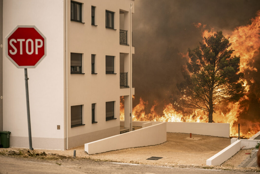 Fire approaches buildings in Grebastica, Croatia, Thursday, July 13, 2023. Evacuation orders were issued in several areas as a wildfire swept through coastal areas of the country. (Mate Gojanovic, SibenikIN via AP)