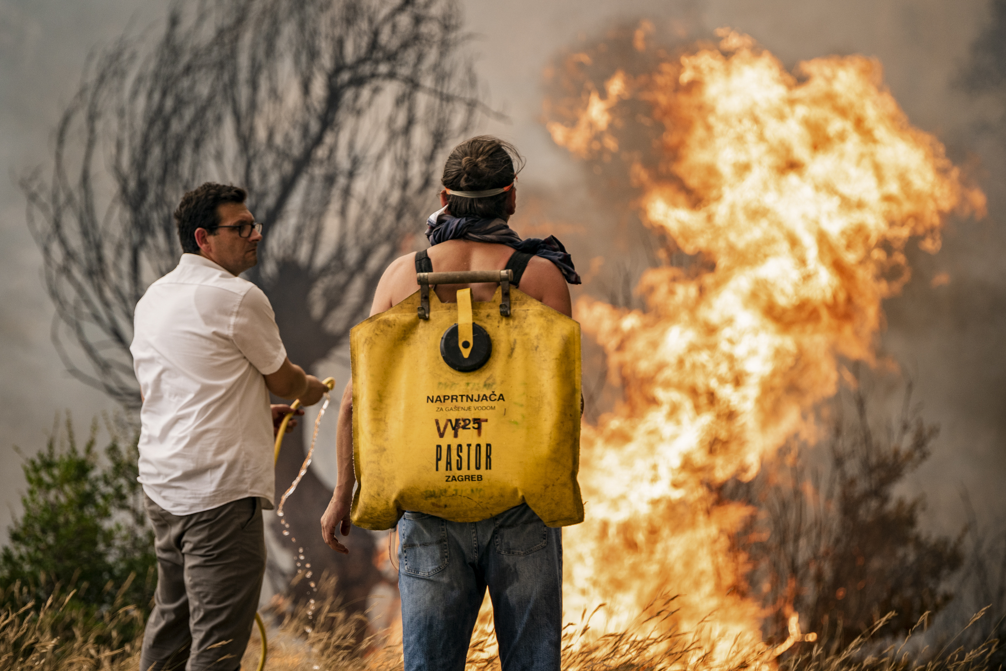Volunteers try to put out the wildfire in Grebastica, Croatia, Thursday, July 13, 2023. Evacuation orders were issued in several areas as a wildfire swept through coastal areas of the country. (Mate Gojanovic, SibenikIN via AP)