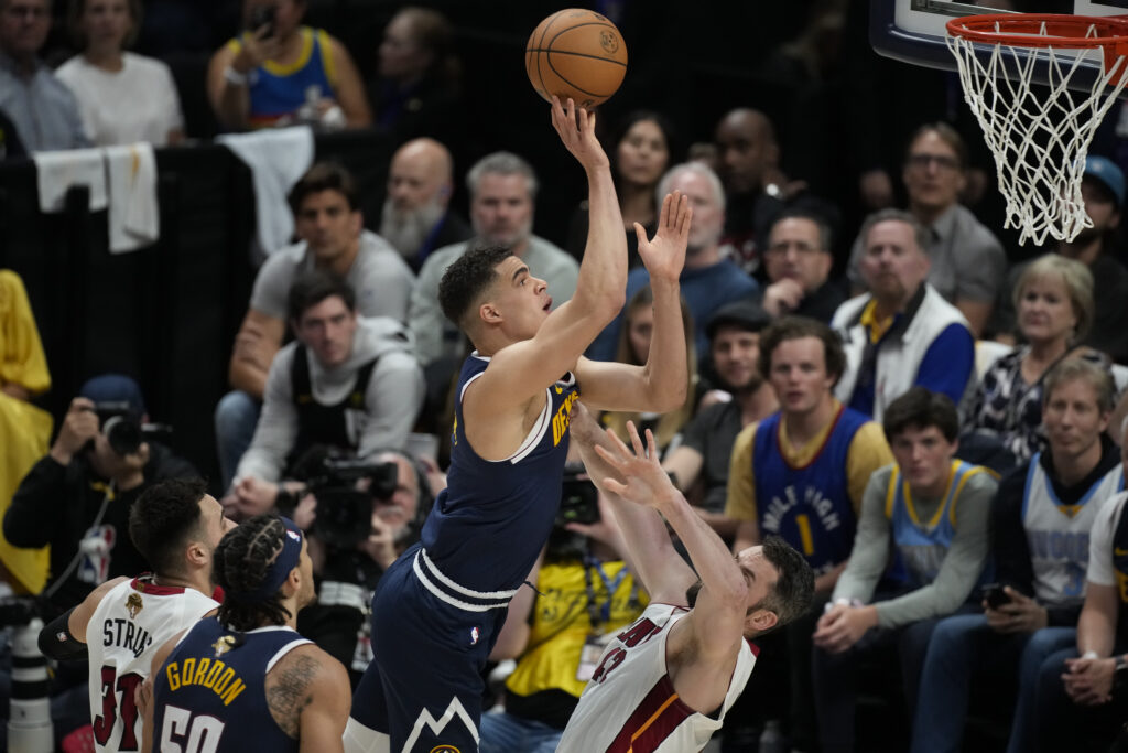 Denver Nuggets forward Michael Porter Jr., center, shoots over Miami Heat forward Kevin Love, right, during the first half of Game 2 of basketball's NBA Finals, Sunday, June 4, 2023, in Denver. (AP Photo/David Zalubowski)