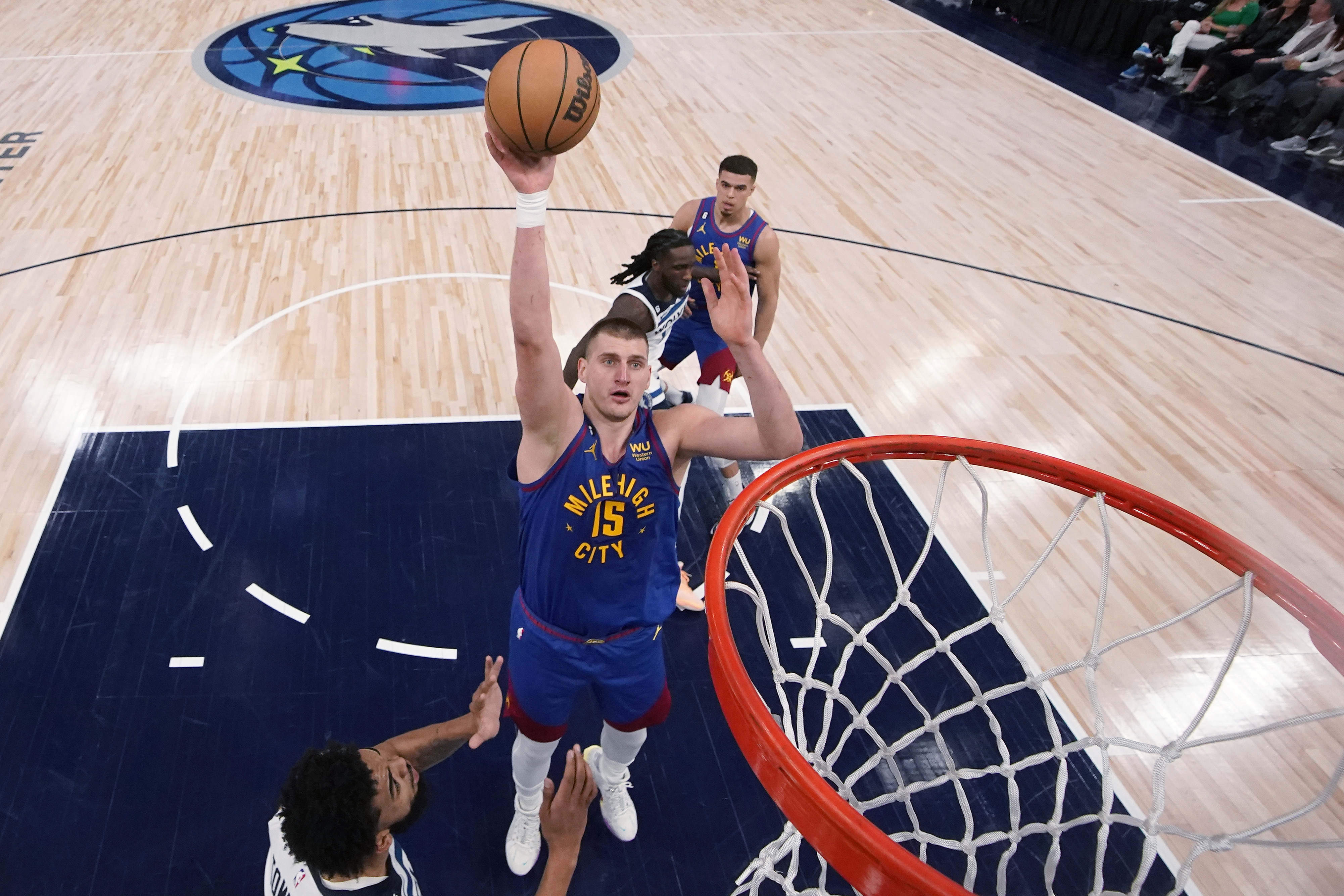 Denver Nuggets center Nikola Jokic (15) shoots next Minnesota Timberwolves' Karl-Anthony Towns, left, during the first half of Game 3 of an NBA basketball first-round playoff series Friday, April 21, 2023, in Minneapolis. (AP Photo/Abbie Parr)