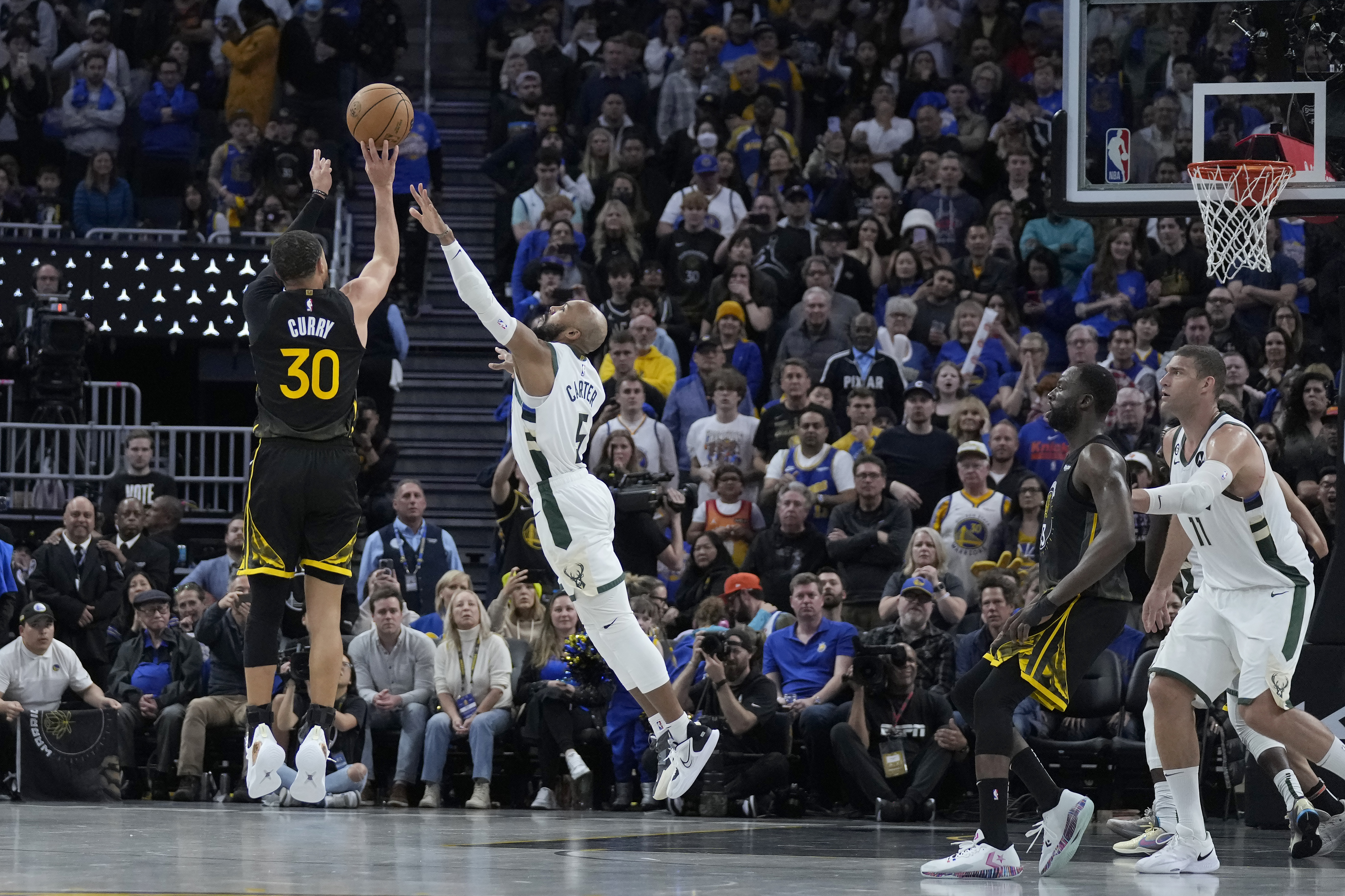 Golden State Warriors guard Stephen Curry (30) makes a 3-point basket against Milwaukee Bucks' Jevon Carter during the second half of an NBA basketball game in San Francisco, Saturday, March 11, 2023. (AP Photo/Jeff Chiu)